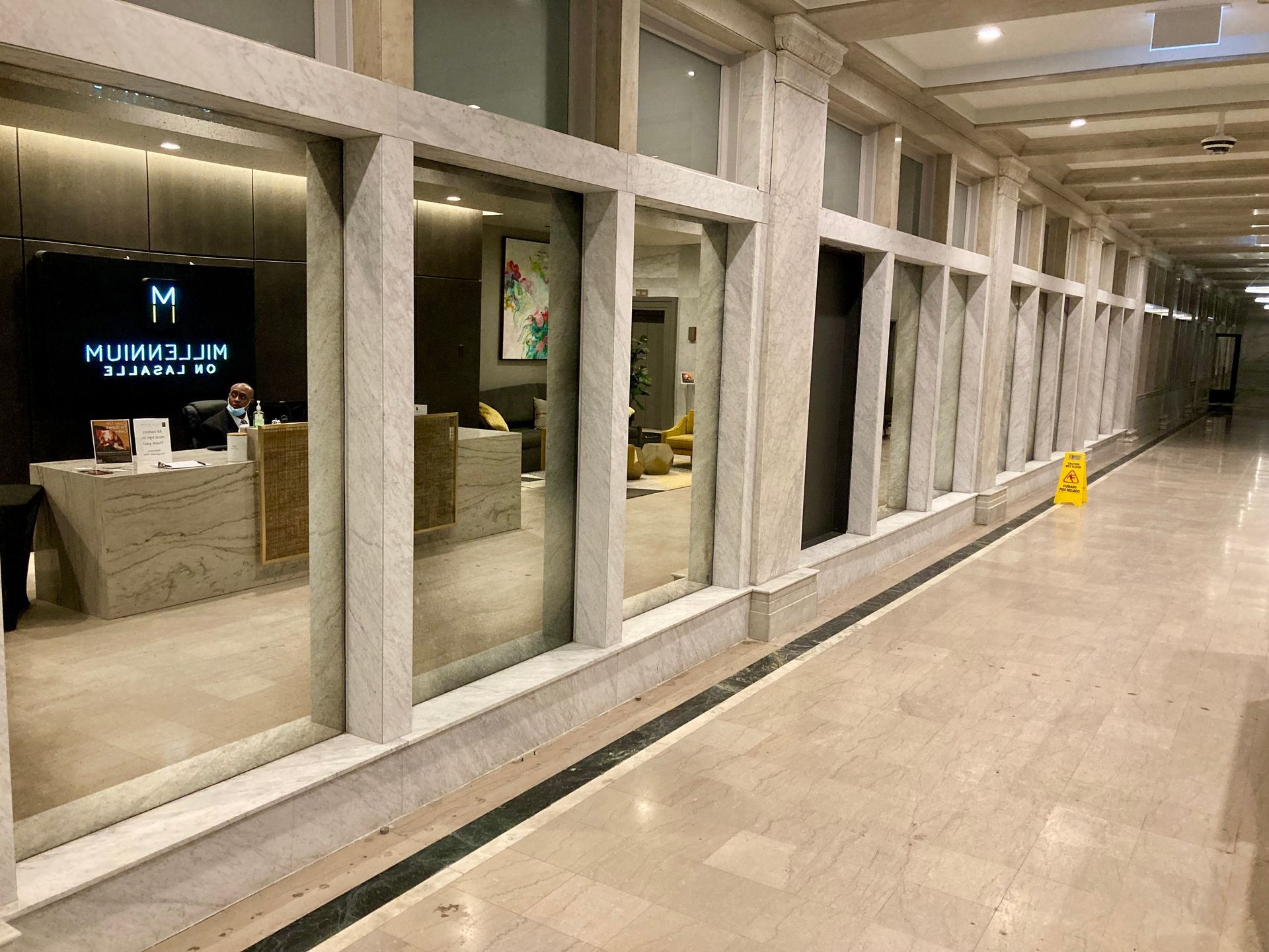 A long hallway with a lot of antique mirrors and a yellow wet floor sign