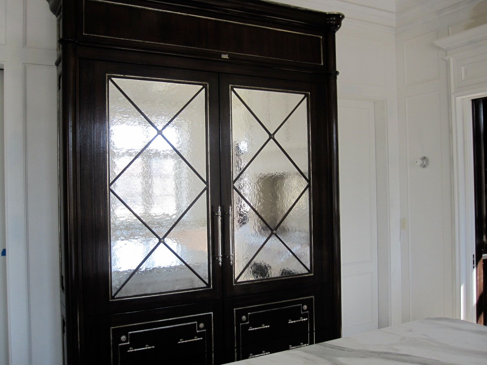 A black cabinet with a antique mirrored door in a bedroom