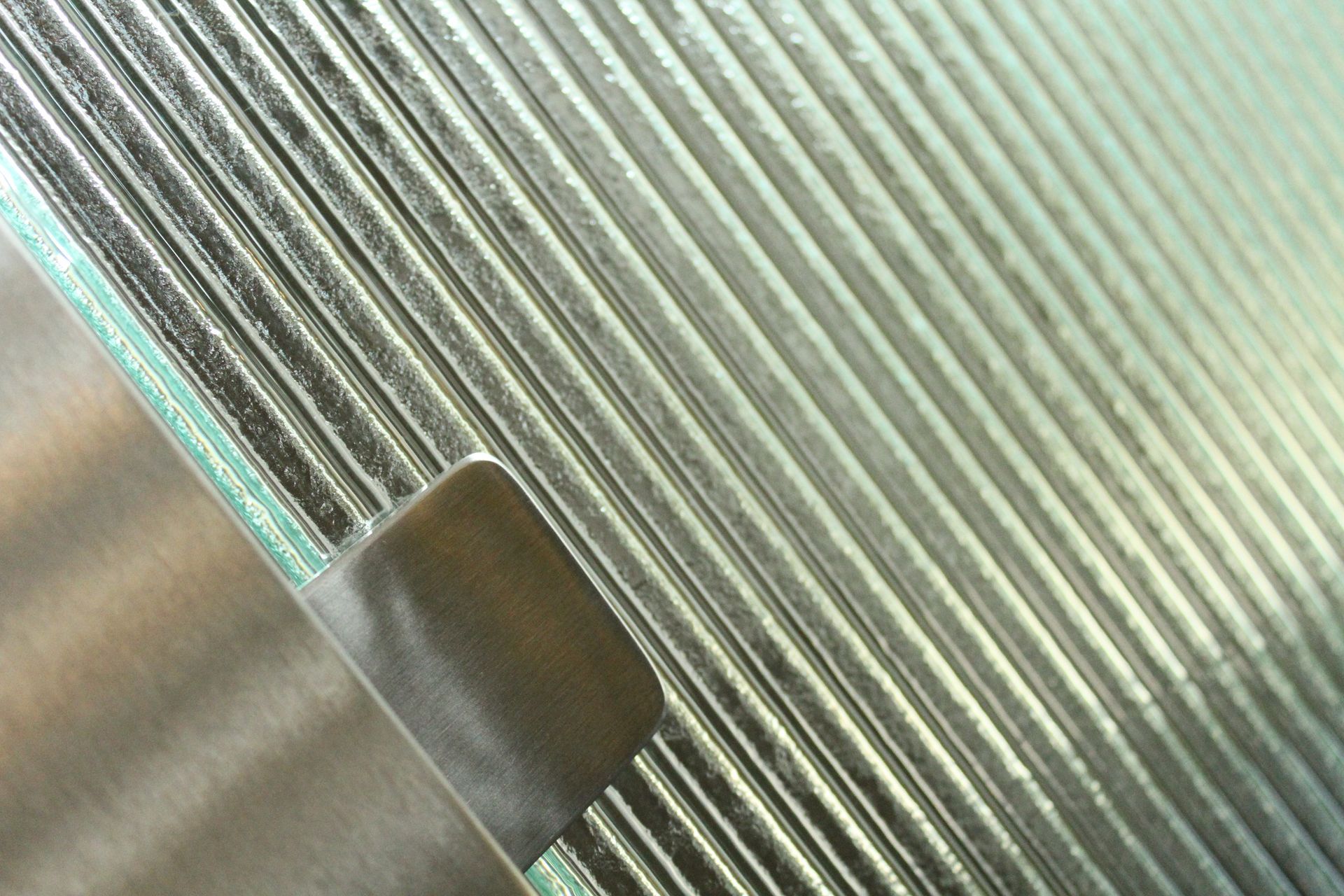 A close-up view of ribbed, textured glass held by a small, dark metallic clip.