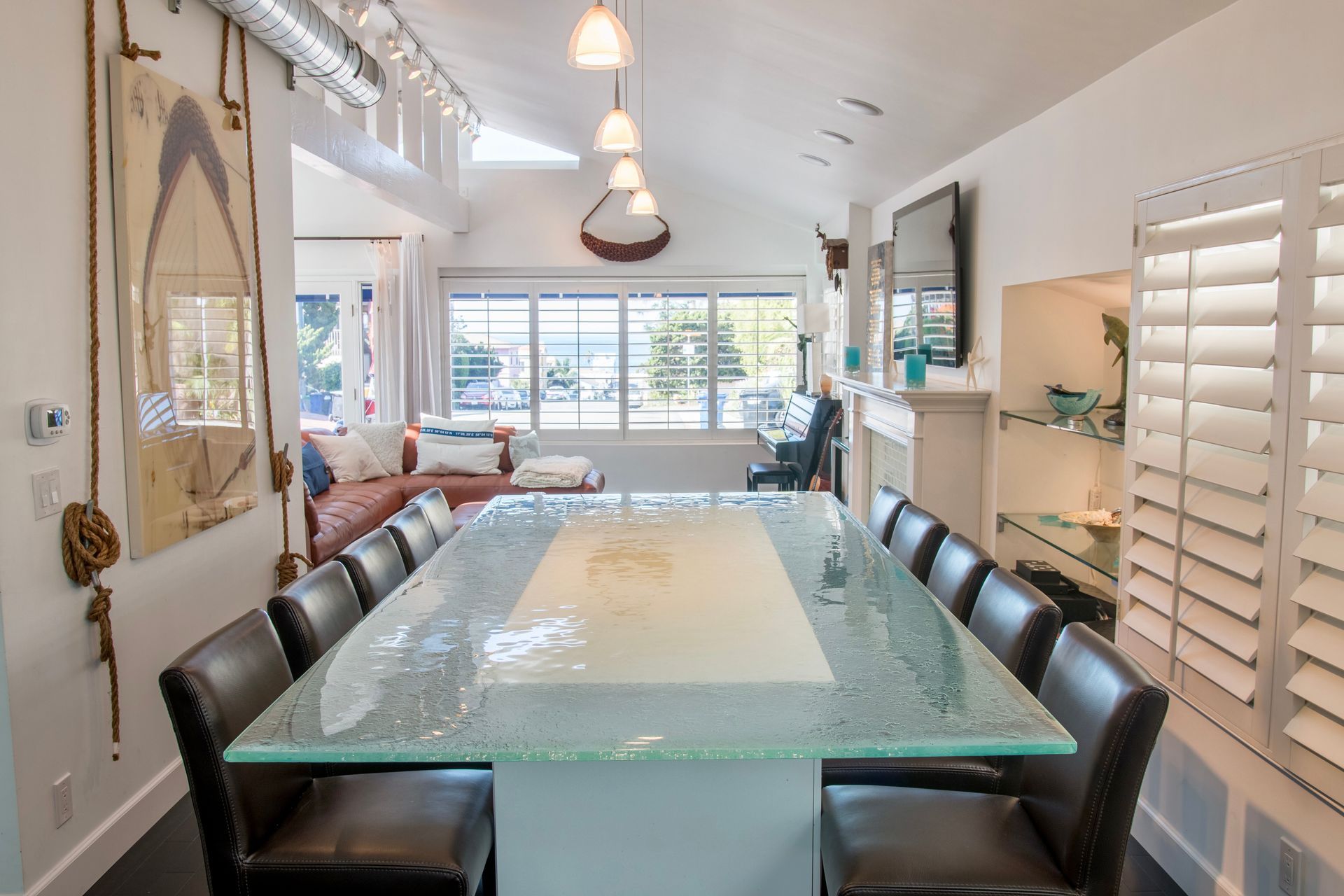 A dining room with a long glass table and chairs.