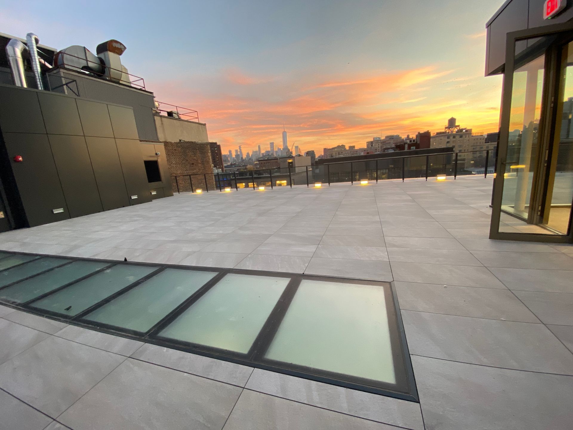 A wallkable glass floor  with a view of the city at sunset