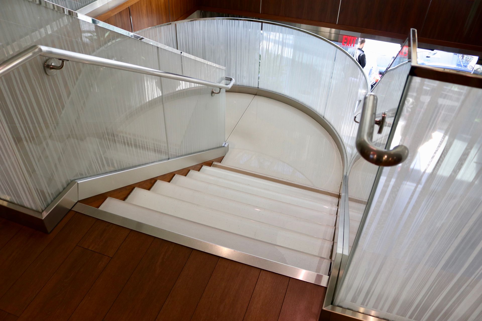 White glass staircase with glass paneling and metal handrails.