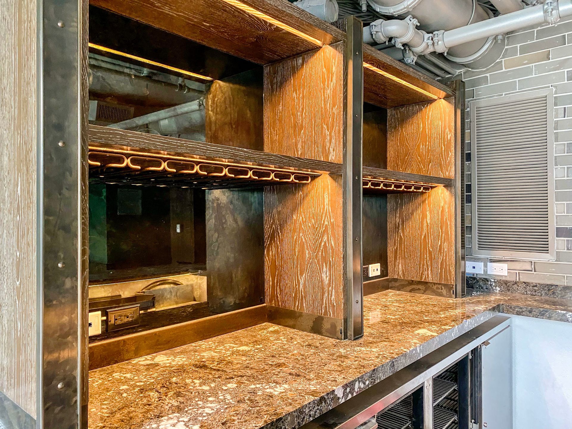 A kitchen with a marble counter top and wooden shelves.