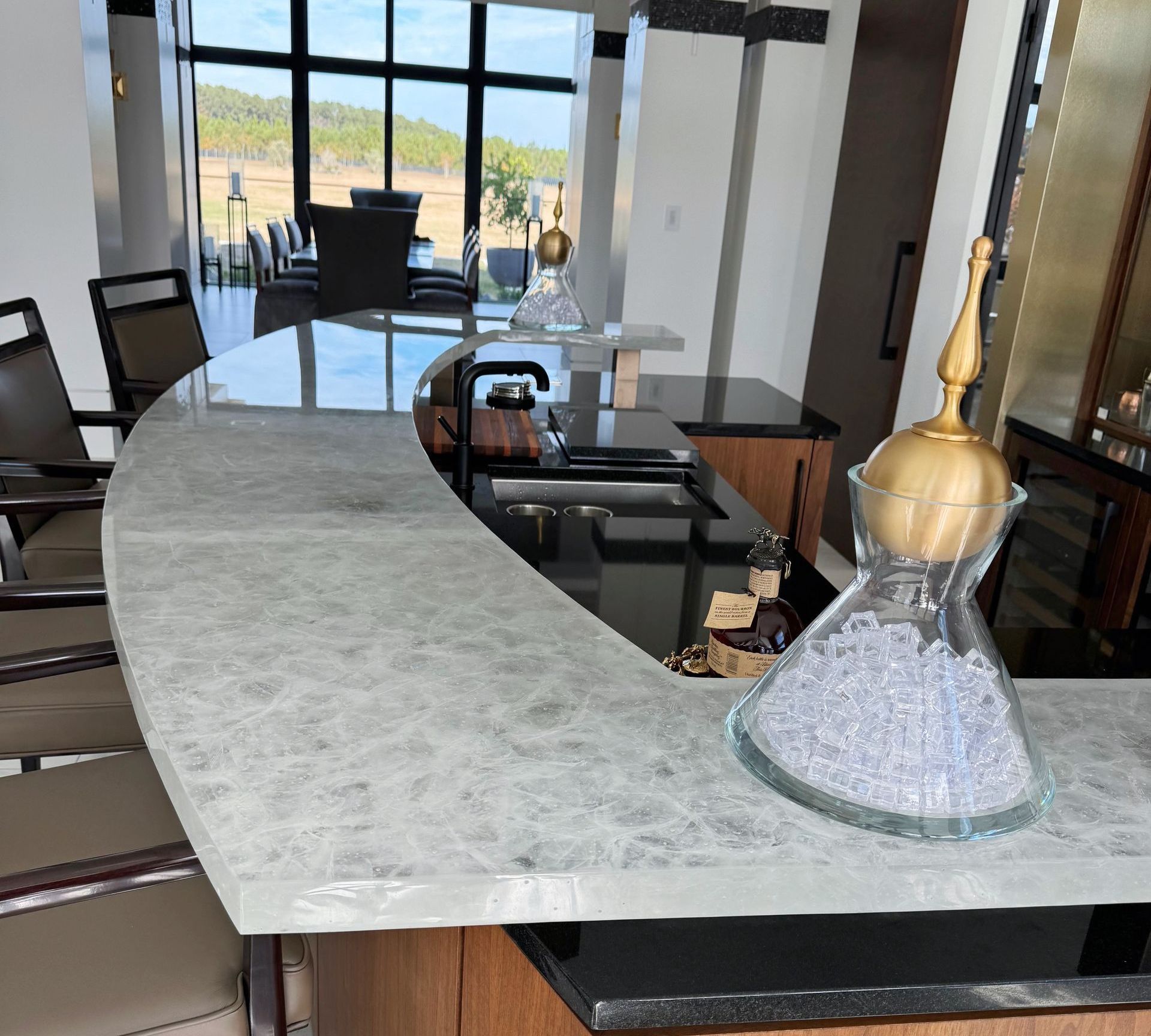 A kitchen with a curved glass counter top and a decanter on it