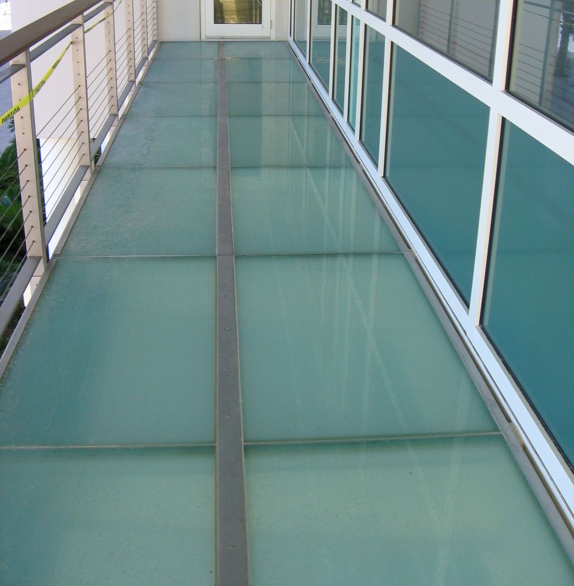Glass walkway between a building and a railing.
