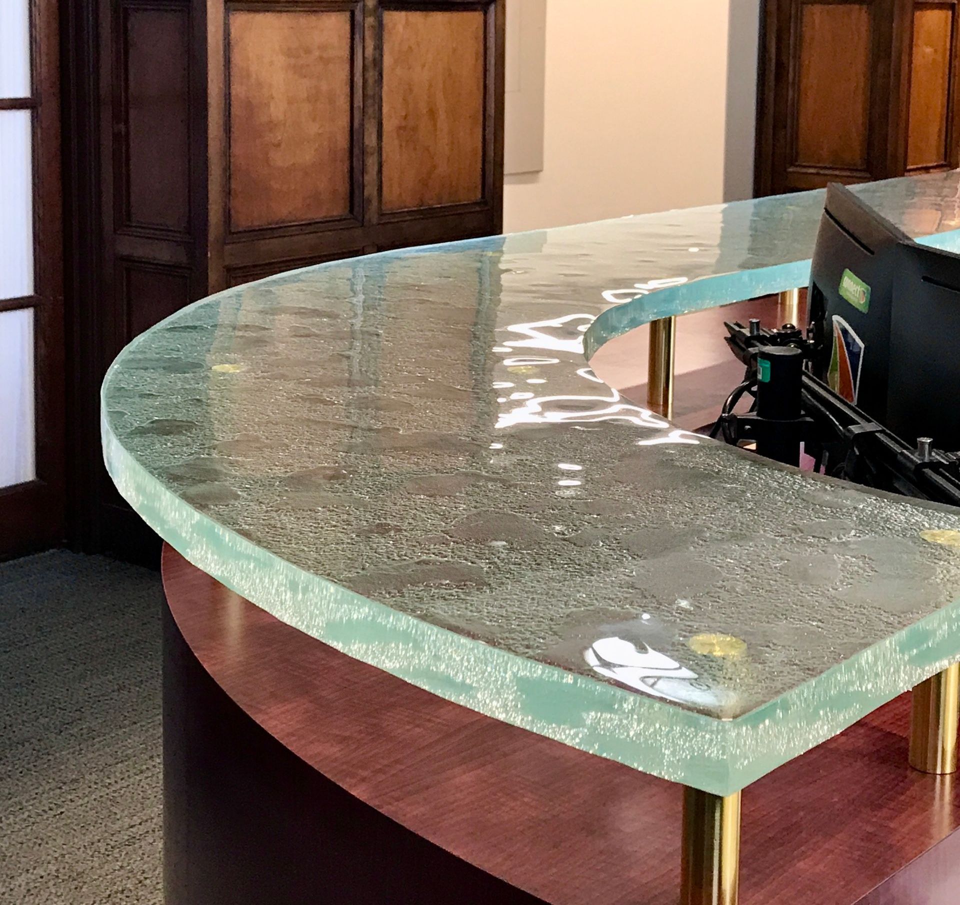 A curved glass counter top with a computer on it