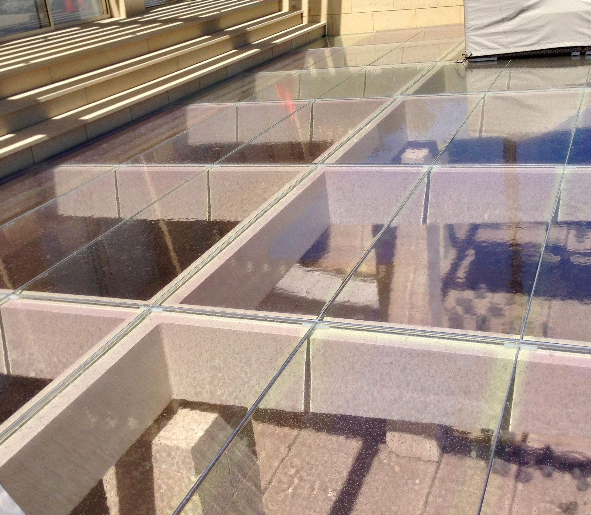 Construction site with clear glass floor tiles laid over a light-colored, rectangular grid structure.