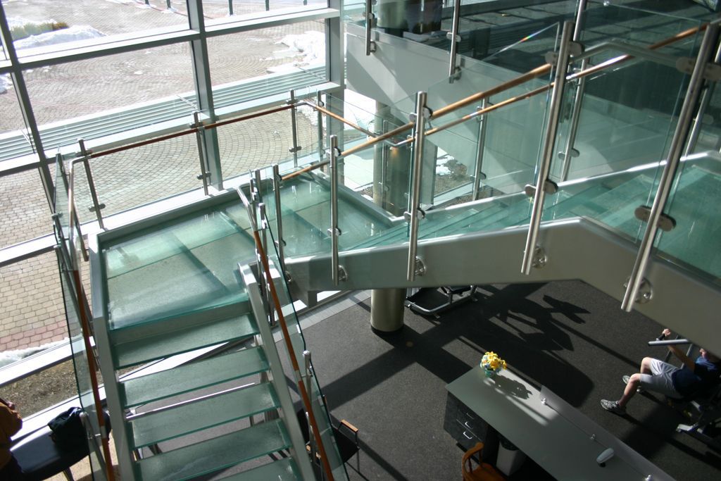 Glass staircase with metal railings in a modern building.