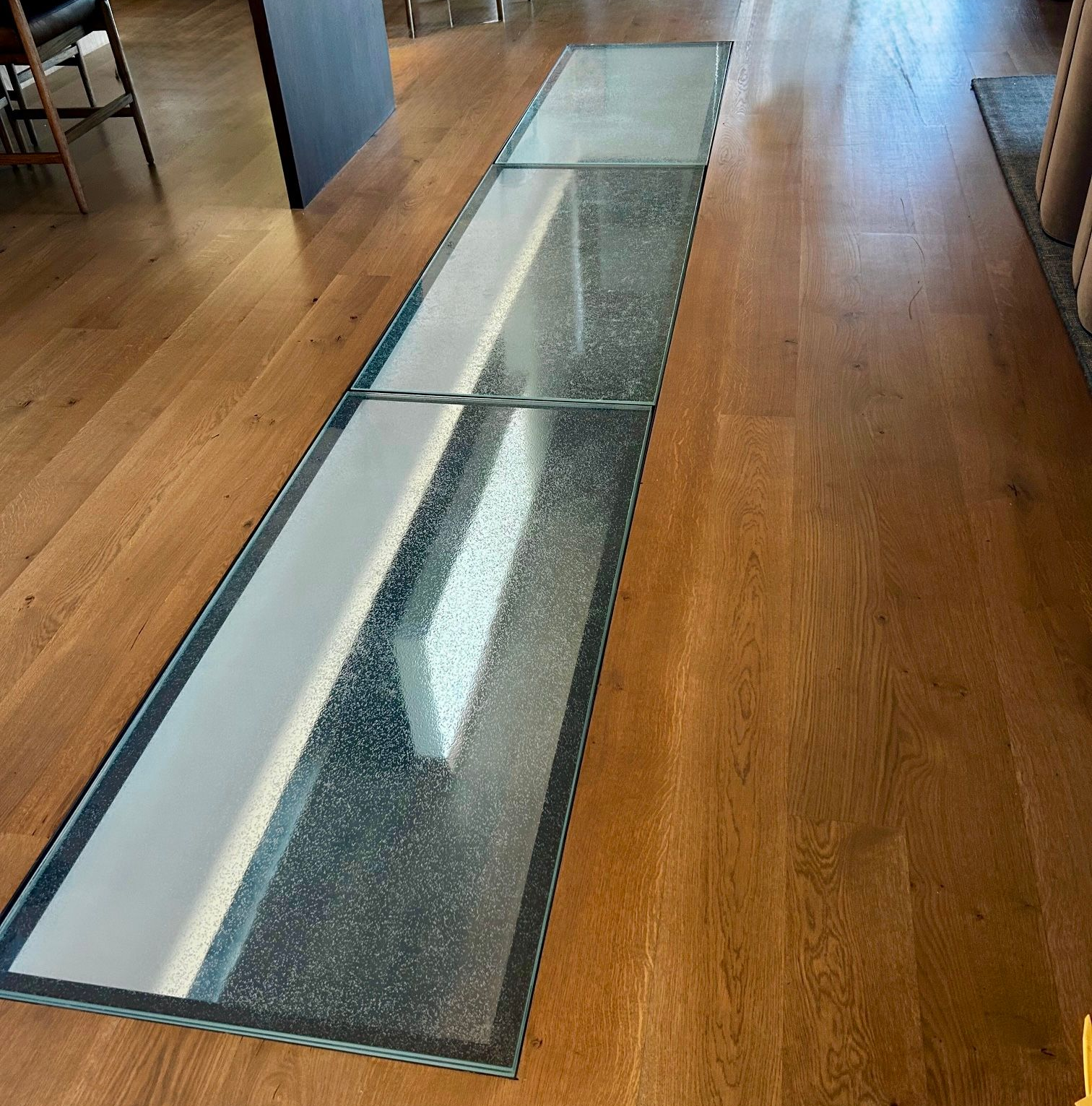 Glass floor panels in a wooden floor, reflecting light.