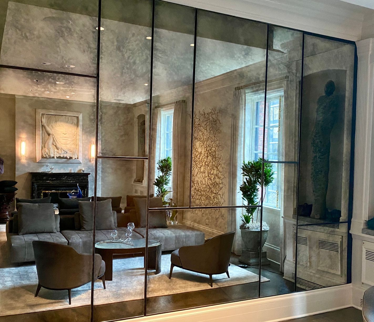 A living room with a couch , chairs , and a mirrored wall.
