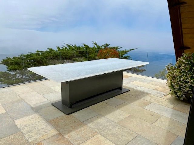 A glass table top on a patio with a view of the ocean