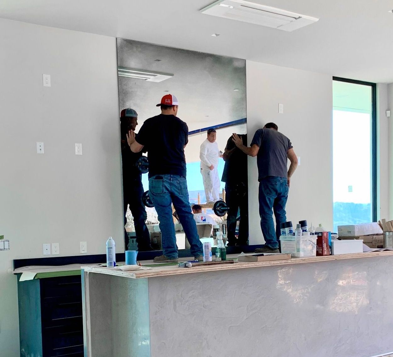 A group of men are working on installing a large antique mirror in a room.