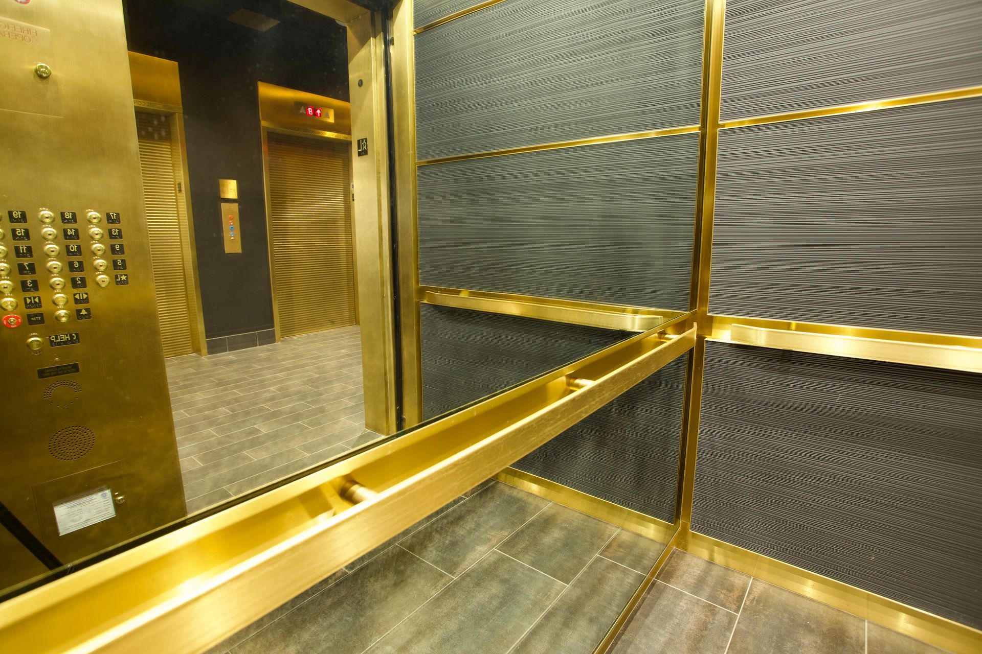 The inside of an elevator with antique mirrors and a  black and gold design