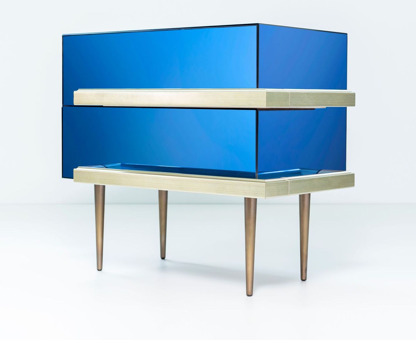 Blue chest of drawers with two gold shelves, supported by gold legs, against a white background.