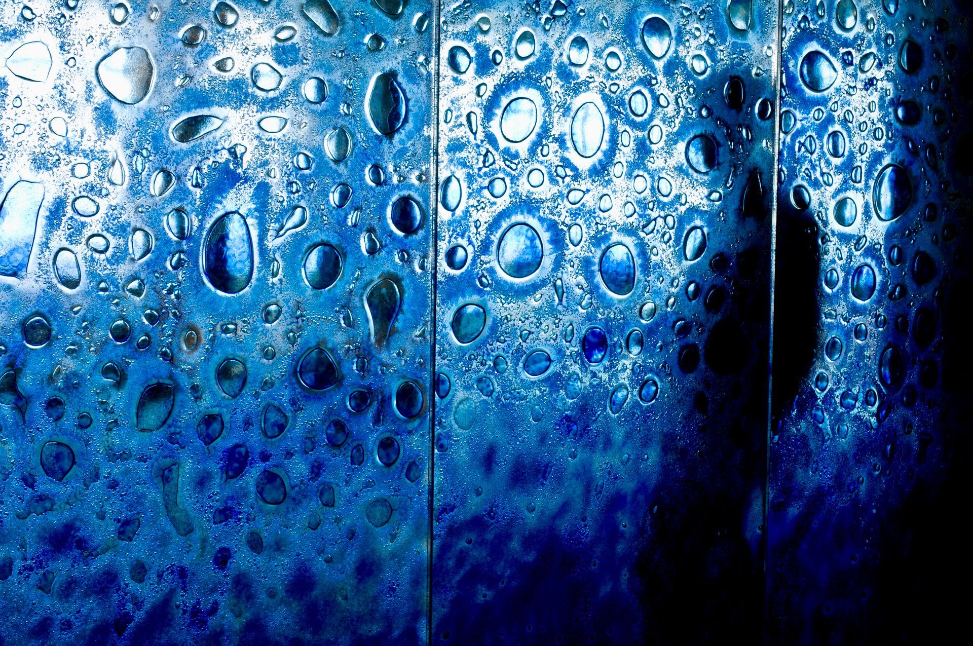 Blue, textured surface with water droplets, reflecting light.