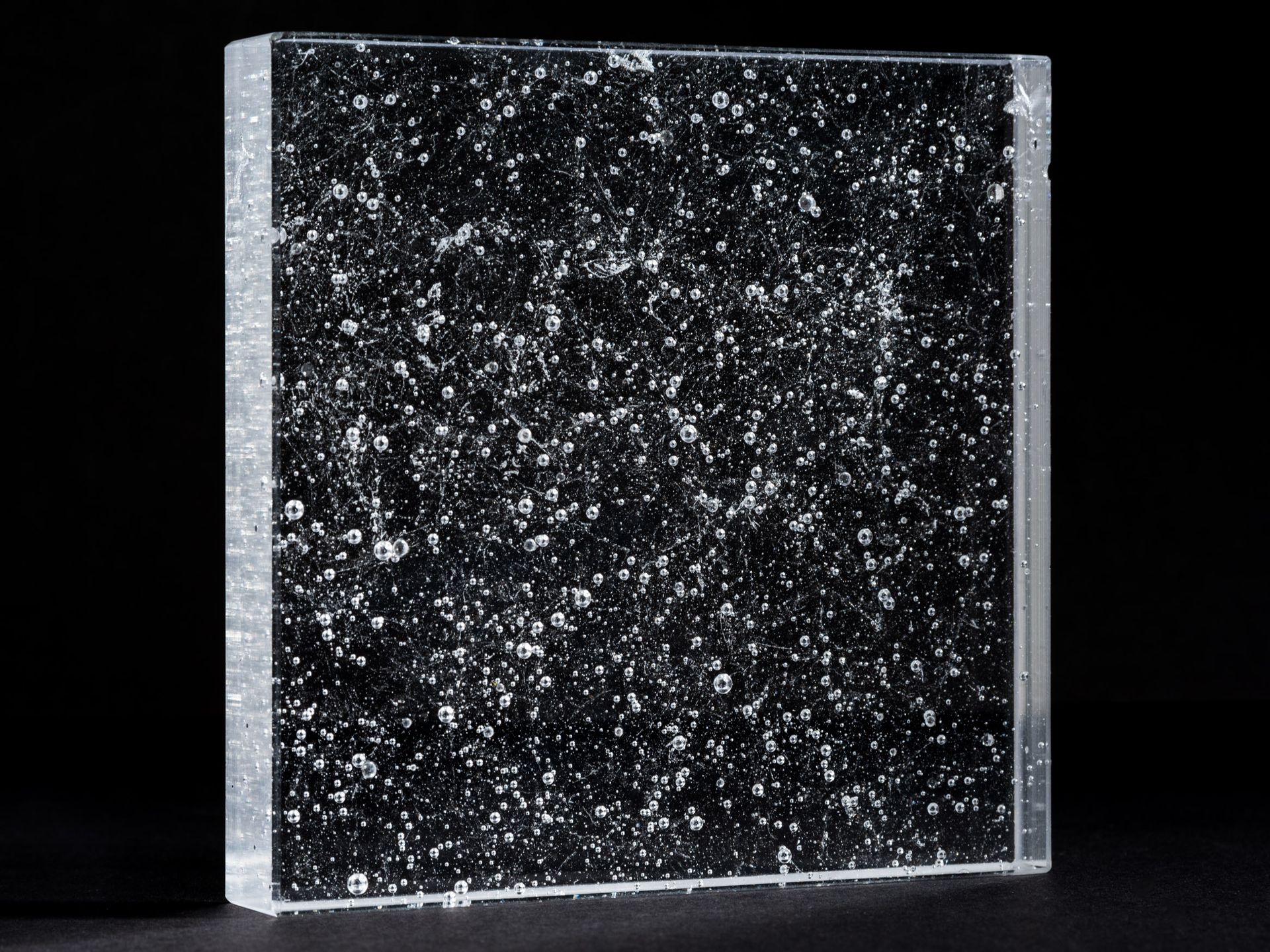 A square piece of glass with a black background and white sparkles on it.