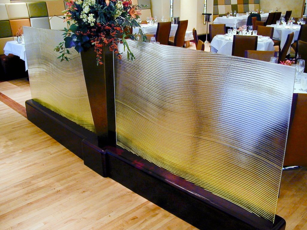 Decorative glass panel with floral arrangement in a restaurant setting. Wooden floor and tables visible in the background.
