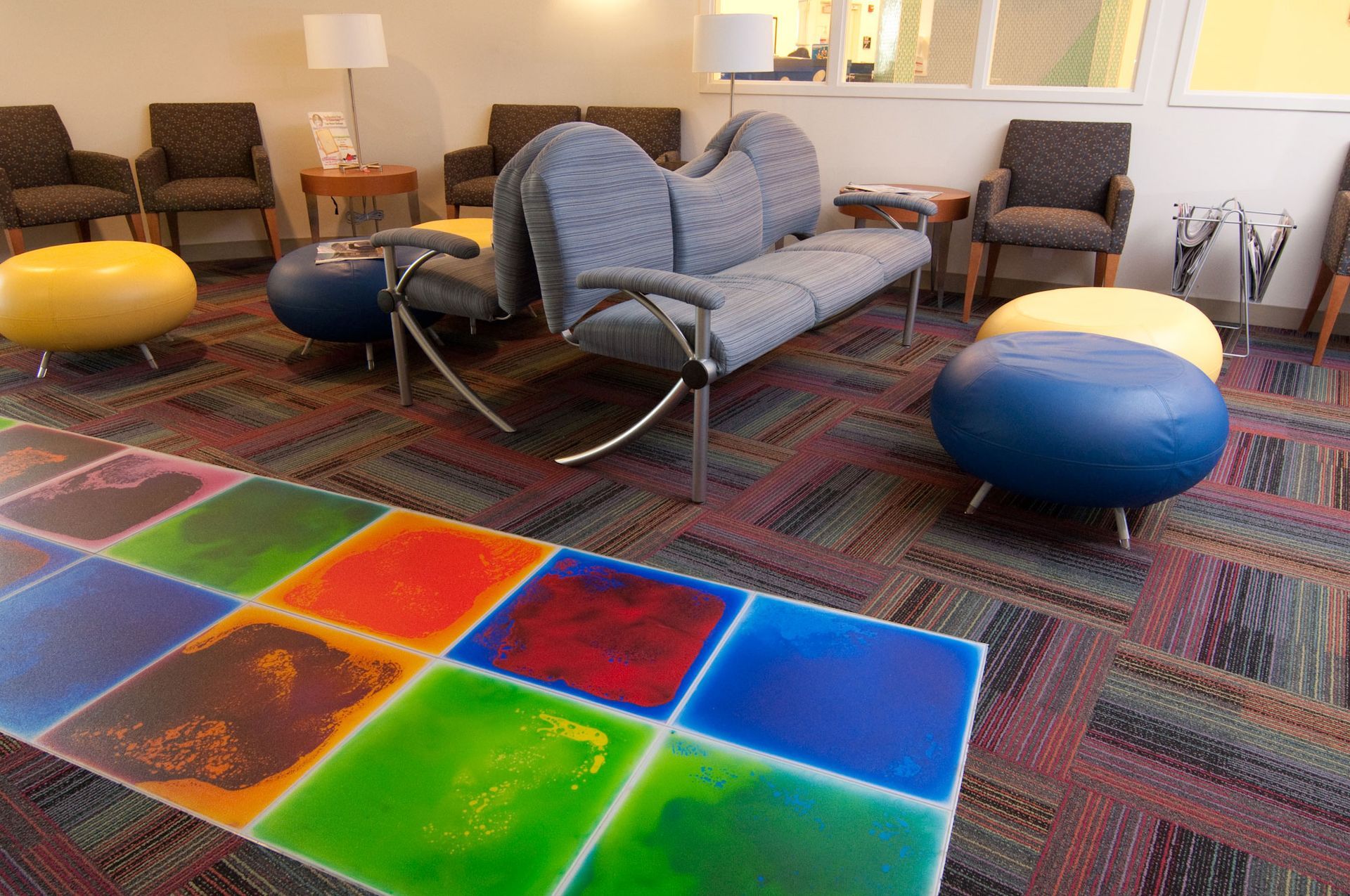 A waiting room with a colorful floor and a couch