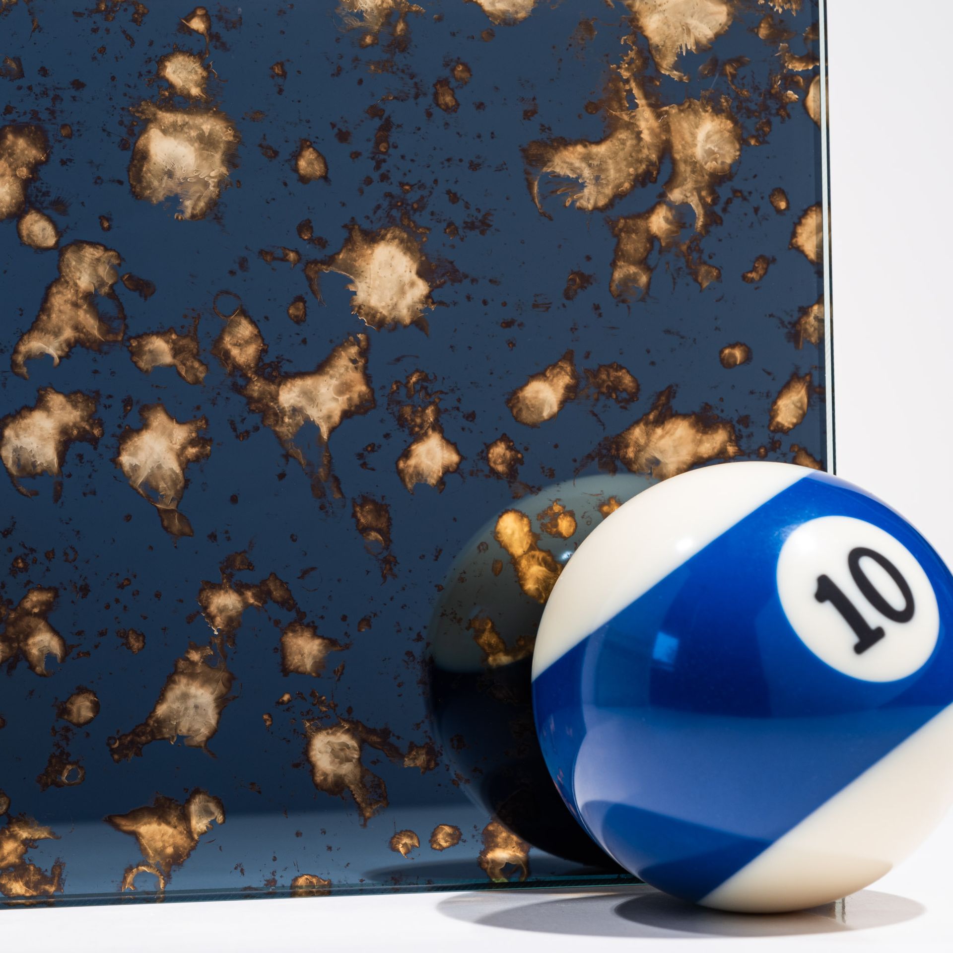 Billiard ball in front of a gold and blue antique mirror finish