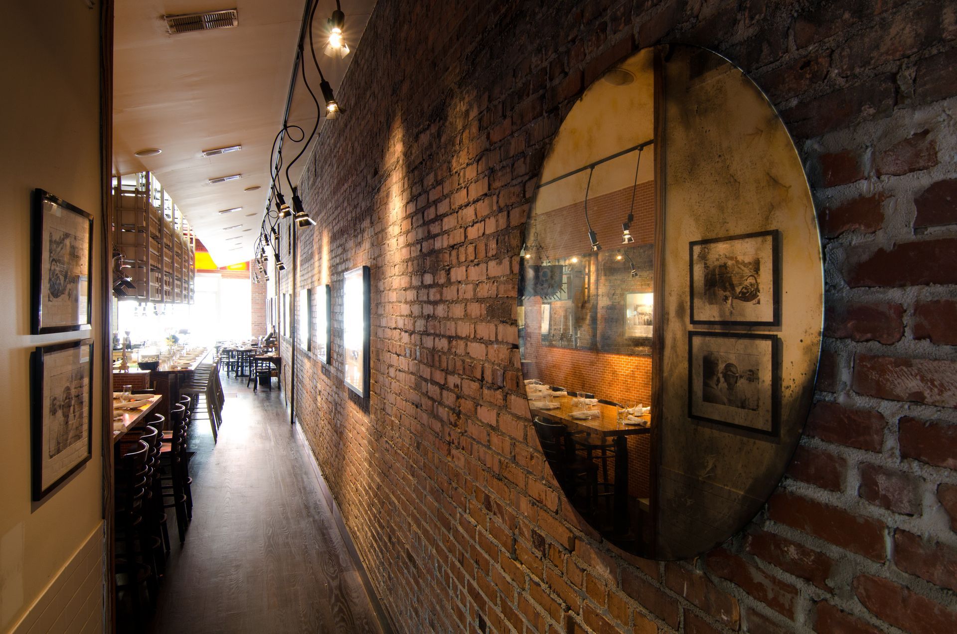 A long hallway with a brick wall and a mirror on the wall.