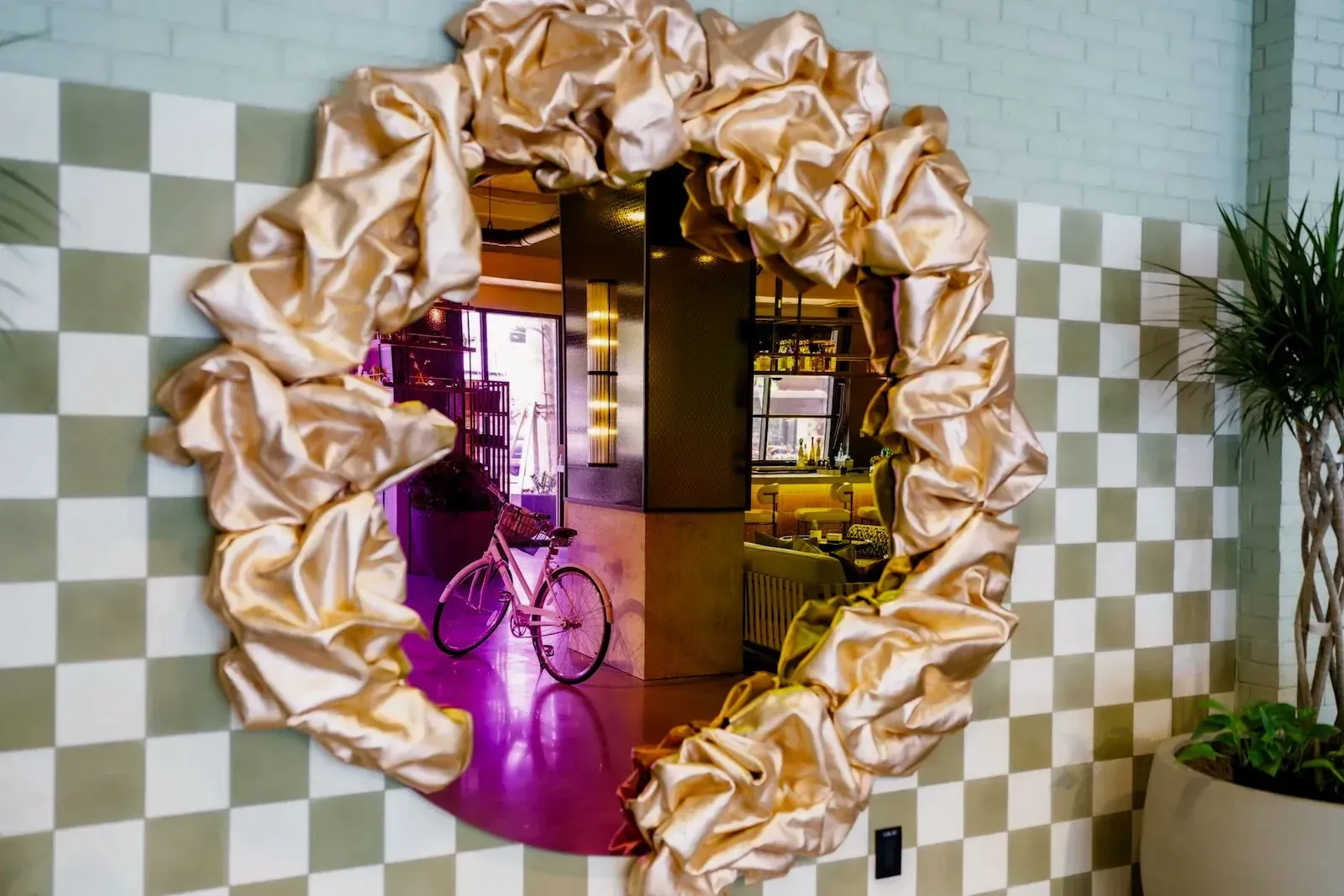 Mirror with gold ruffled frame reflecting a room with a bicycle.