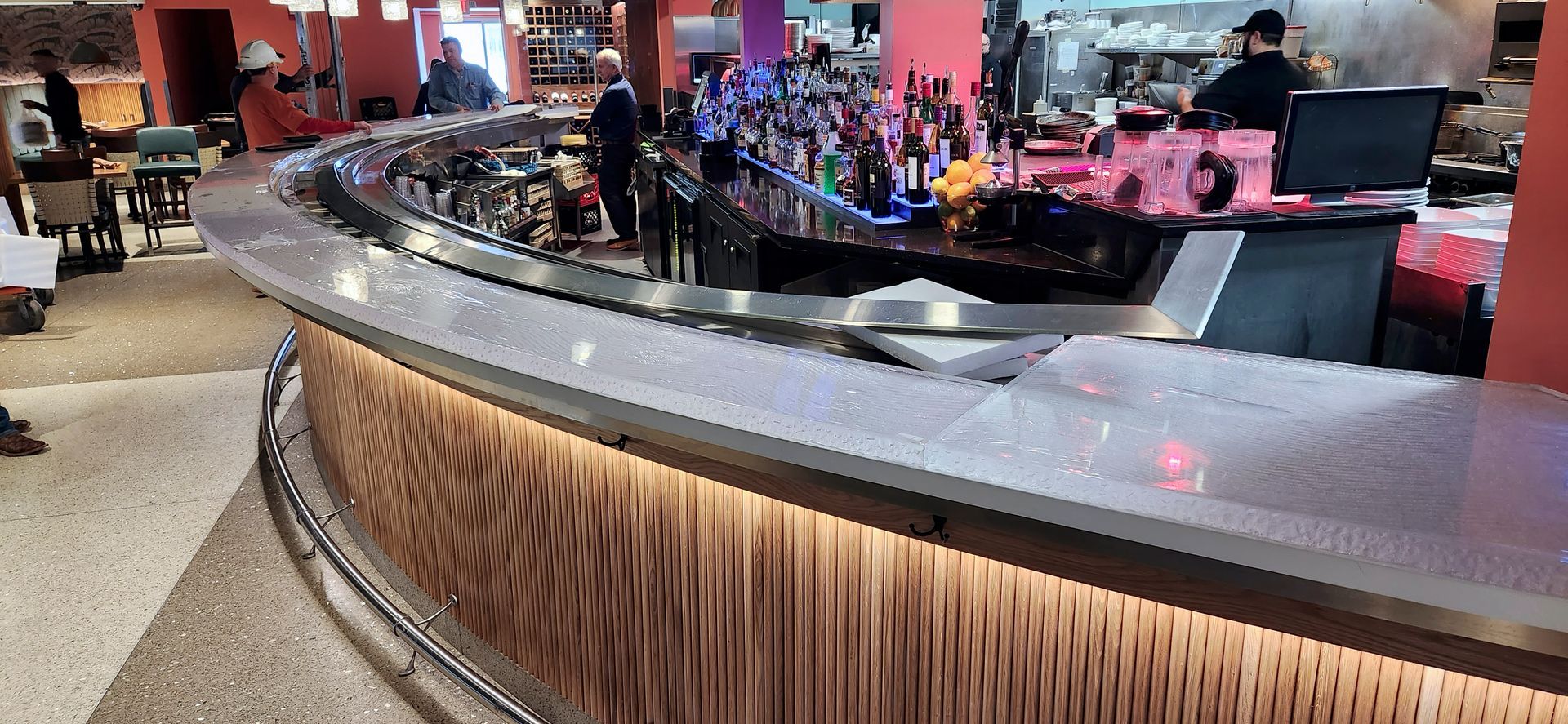 A glass counter top bar in a restaurant with people standing behind it.