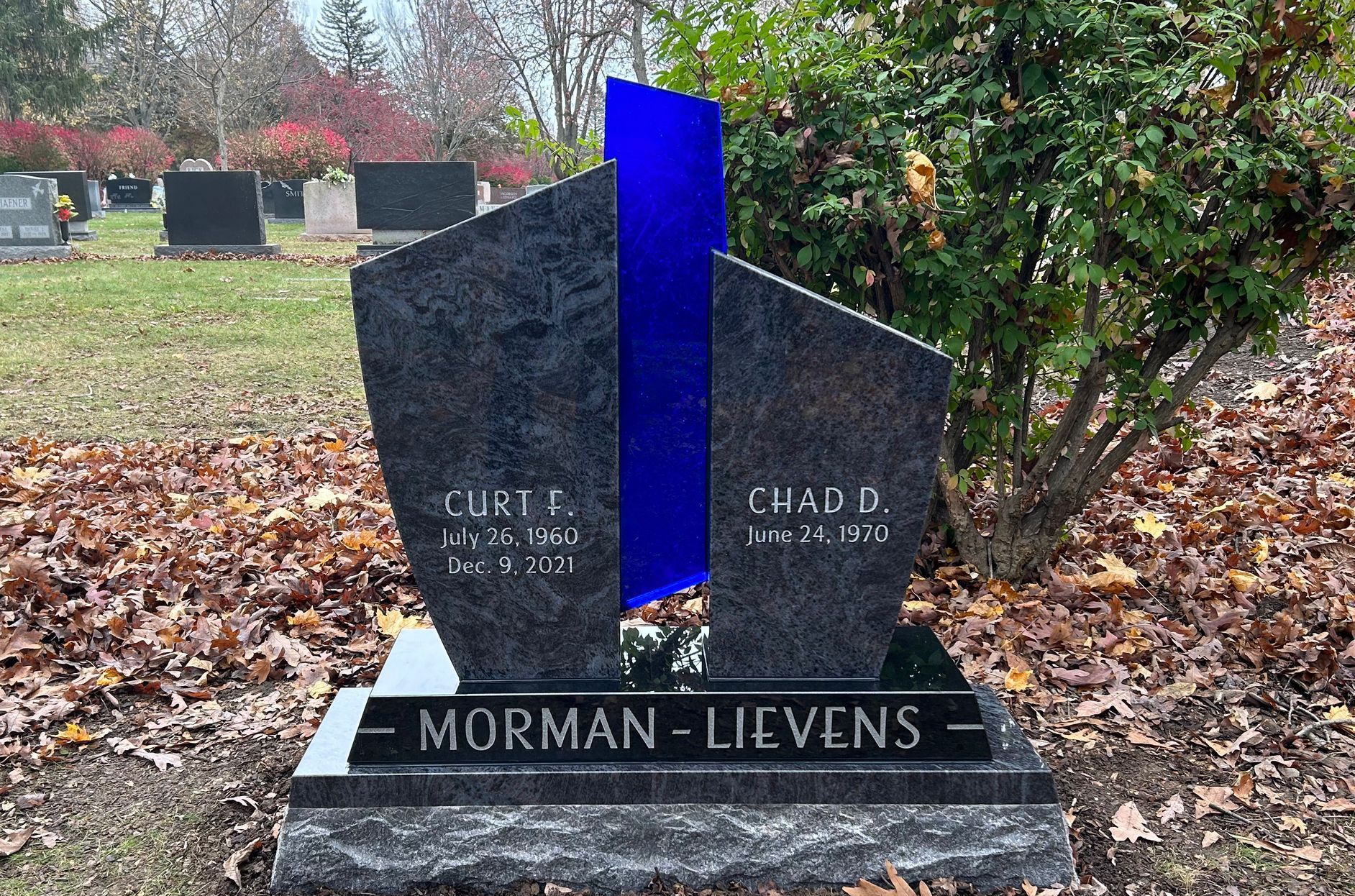 A custom glass headstone with gray stone on the side and a center of blue TRUE Colors Thick Glass.