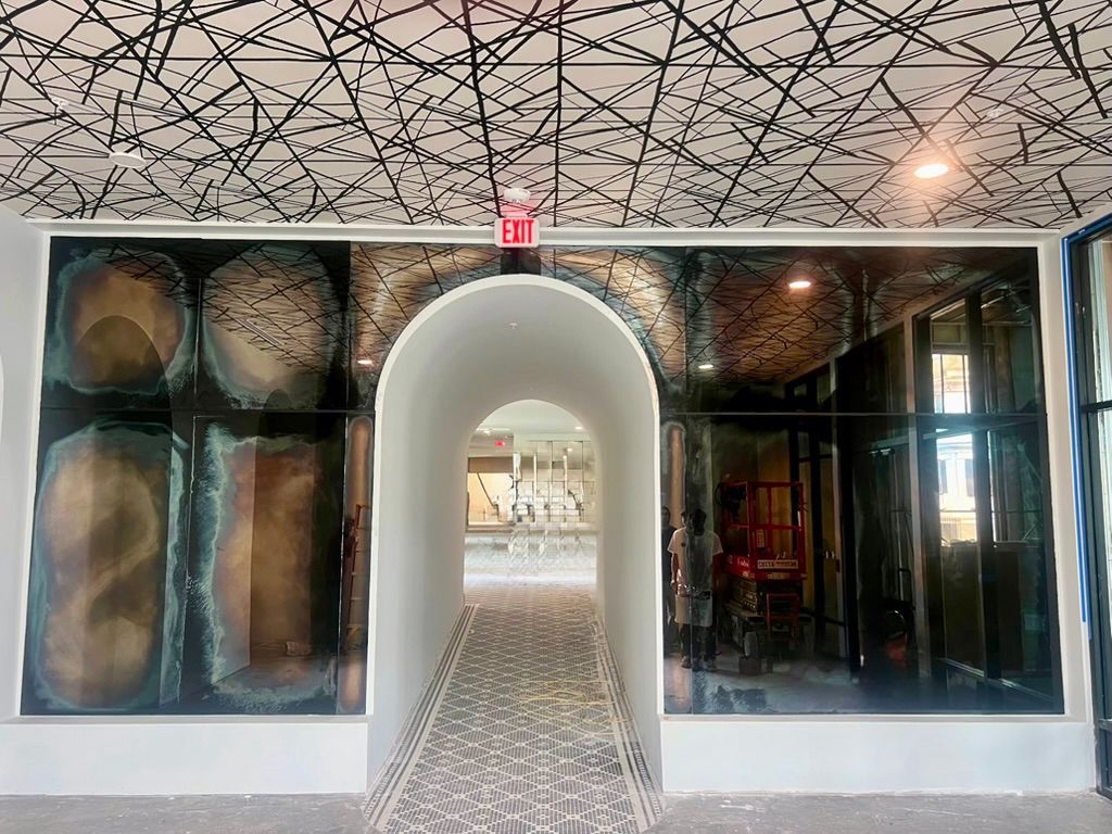 An arched entryway with a patterned ceiling and tile floor leads to a shopping area. antique mirrors