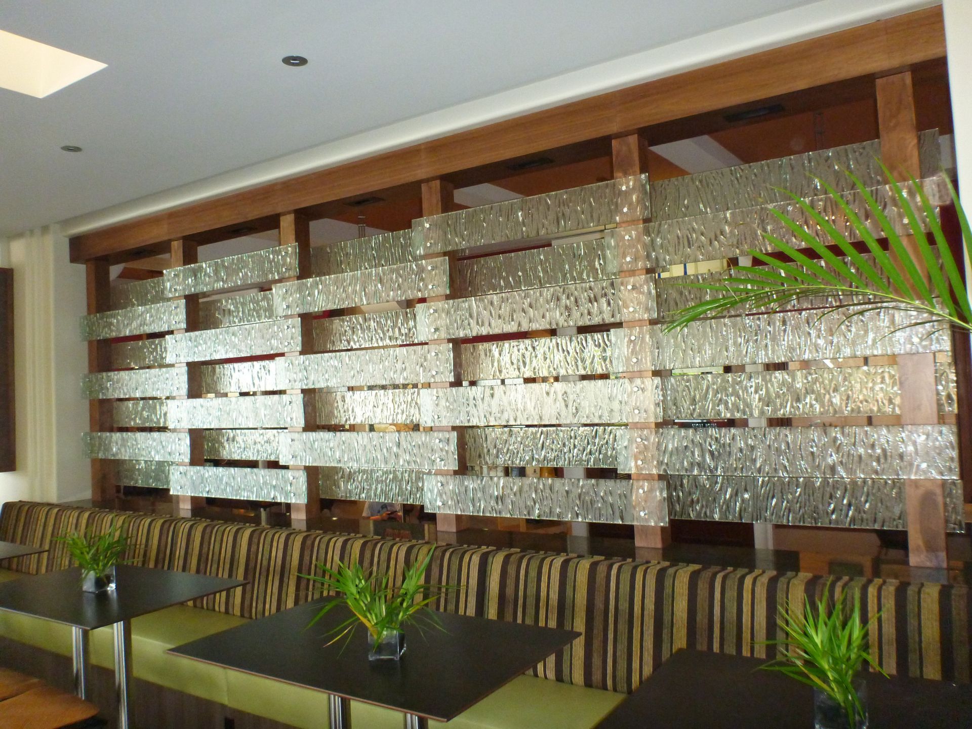 A restaurant booth seating area featuring a decorative wooden wall partition with inset textured glass panels.