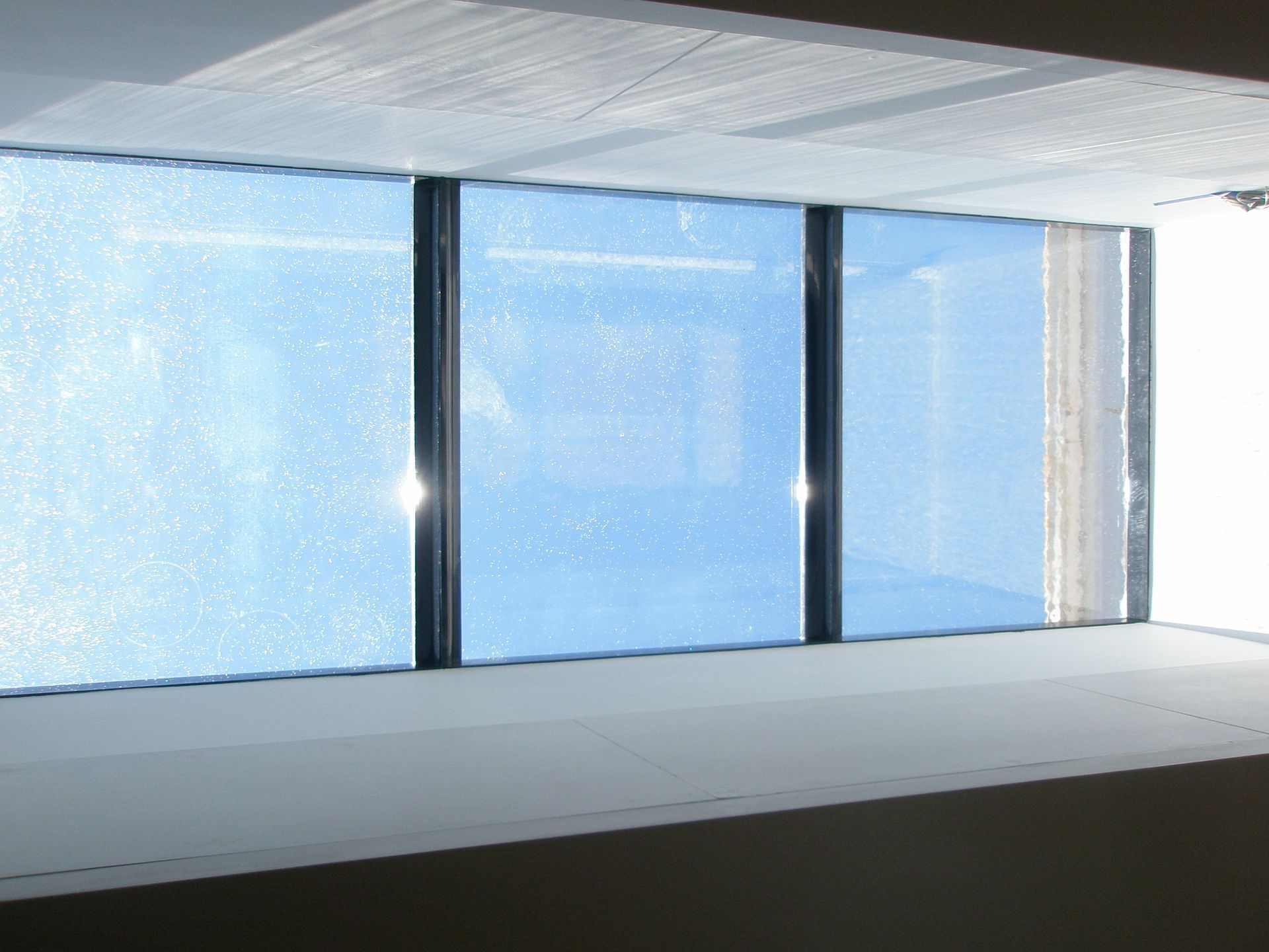 Skylight window with a blue sky view, framed by black trim, with a white interior surrounding it.