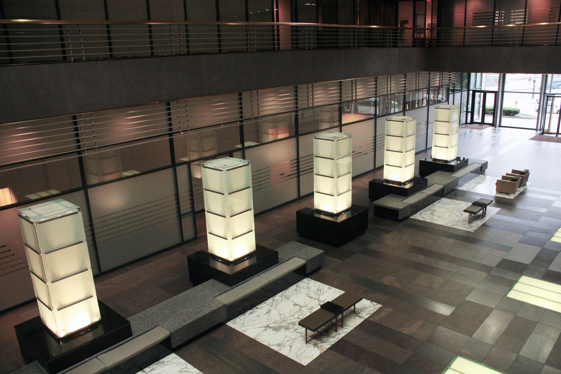 Lobby with large glowing pillars, seating, and frosted glass walls.