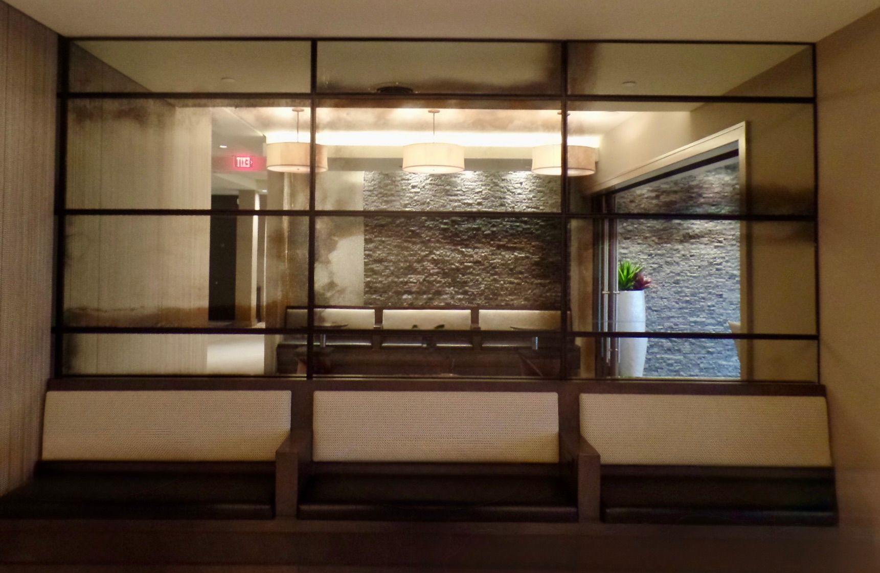 A row of three neutral-toned bench seats in front of a windowed wall, showcasing a modern indoor waiting area.