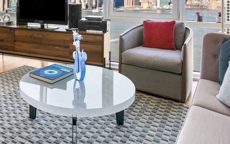 A living room with a couch , chair, circle glass table and television.