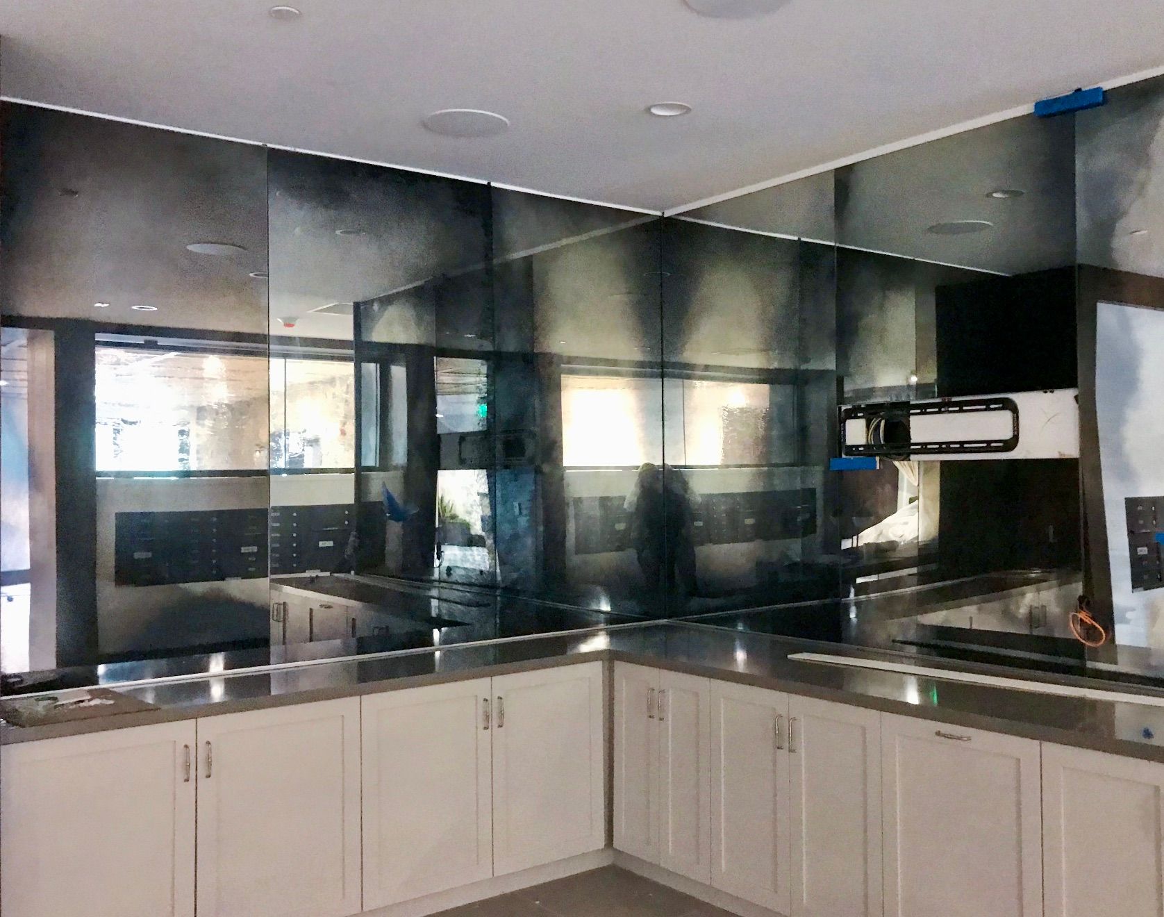 A kitchen with white cabinets and a large antique mirror on the wall.