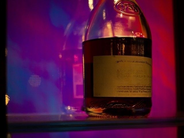 A bottle of alcohol set against a bar shelf using dichroic glass.