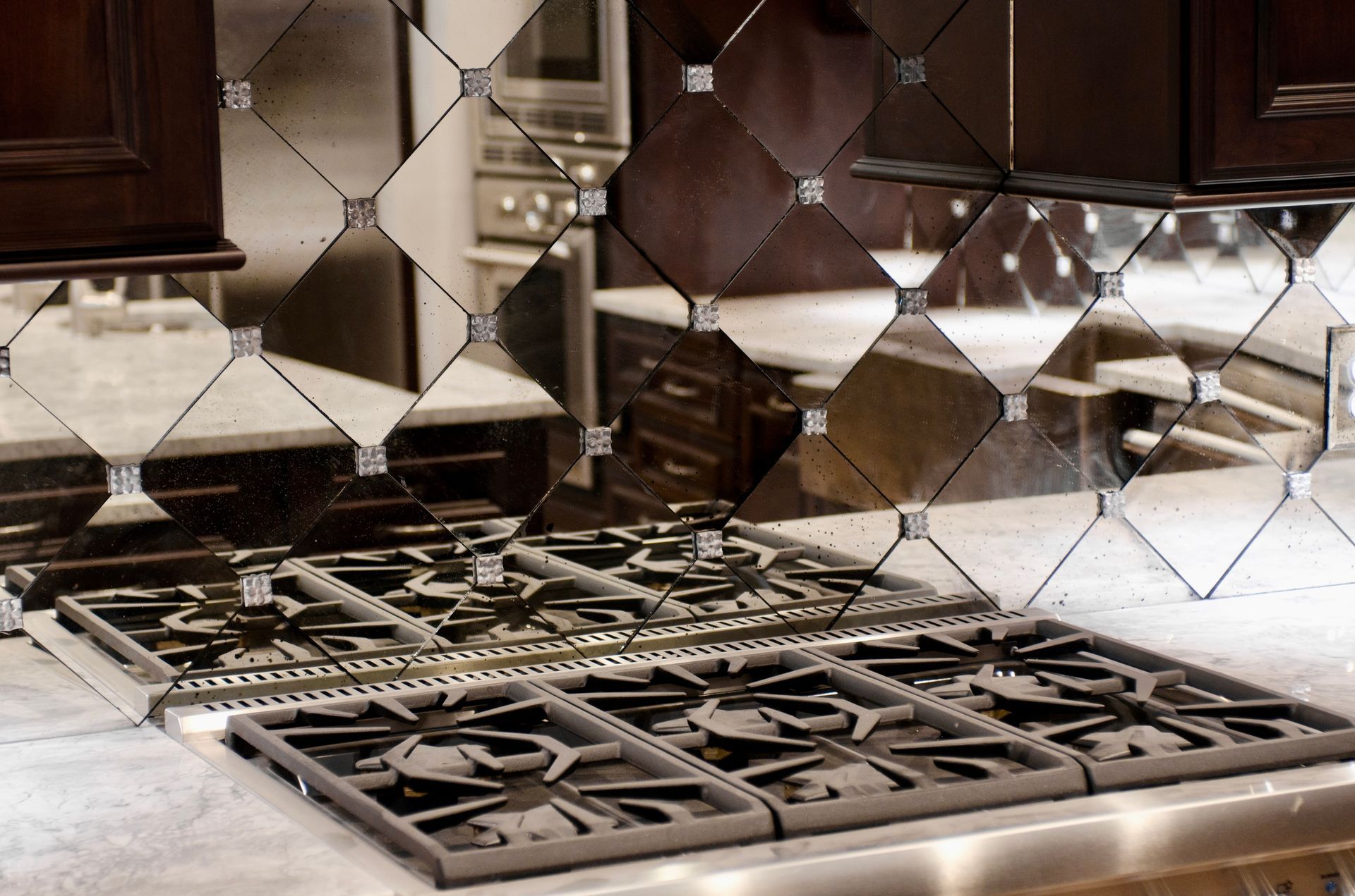 Close-up of a kitchen stovetop with a decorative, mirrored diamond-patterned tile backsplash.