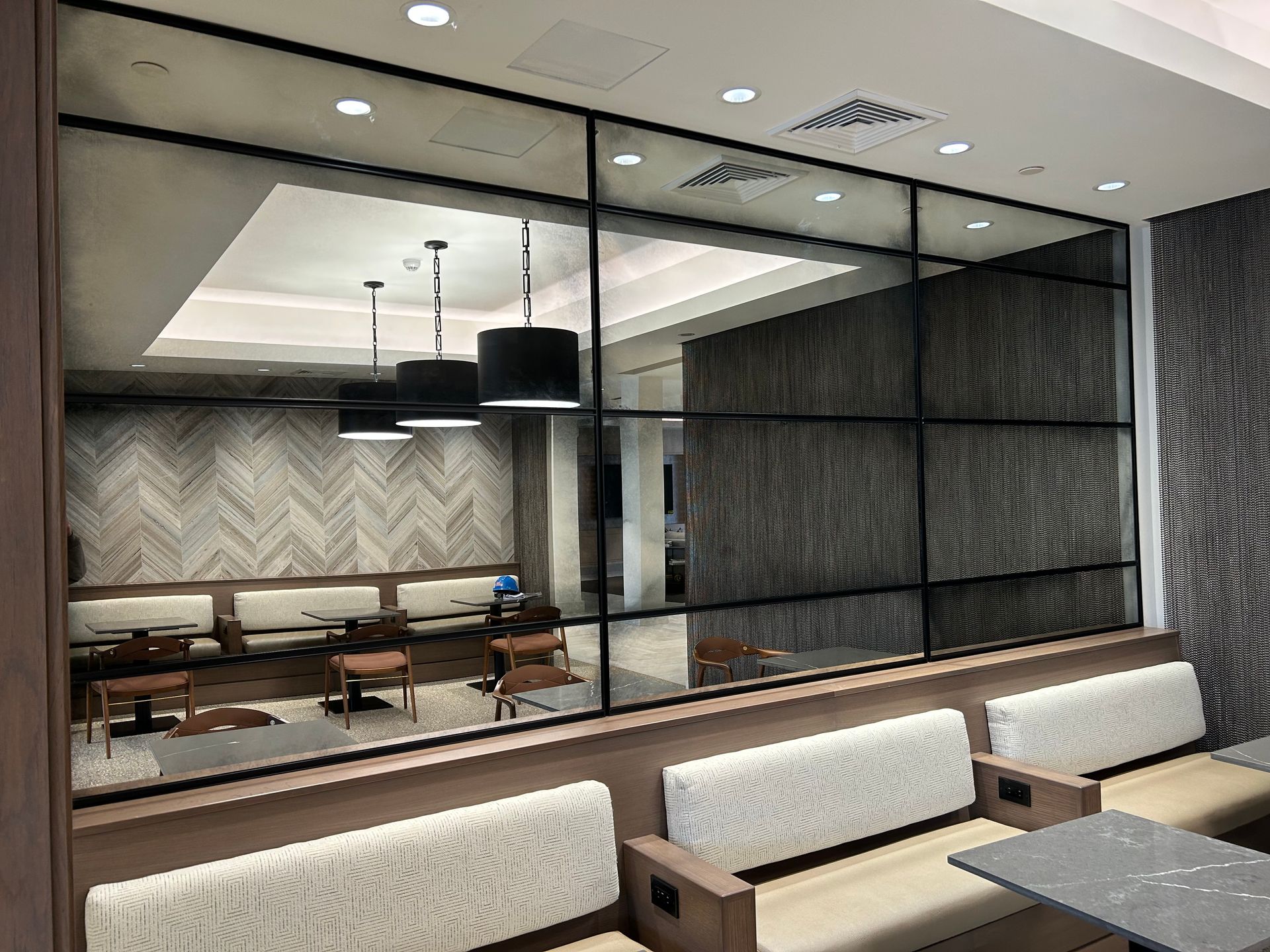 A restaurant with tables and chairs and a large mirror on the wall.