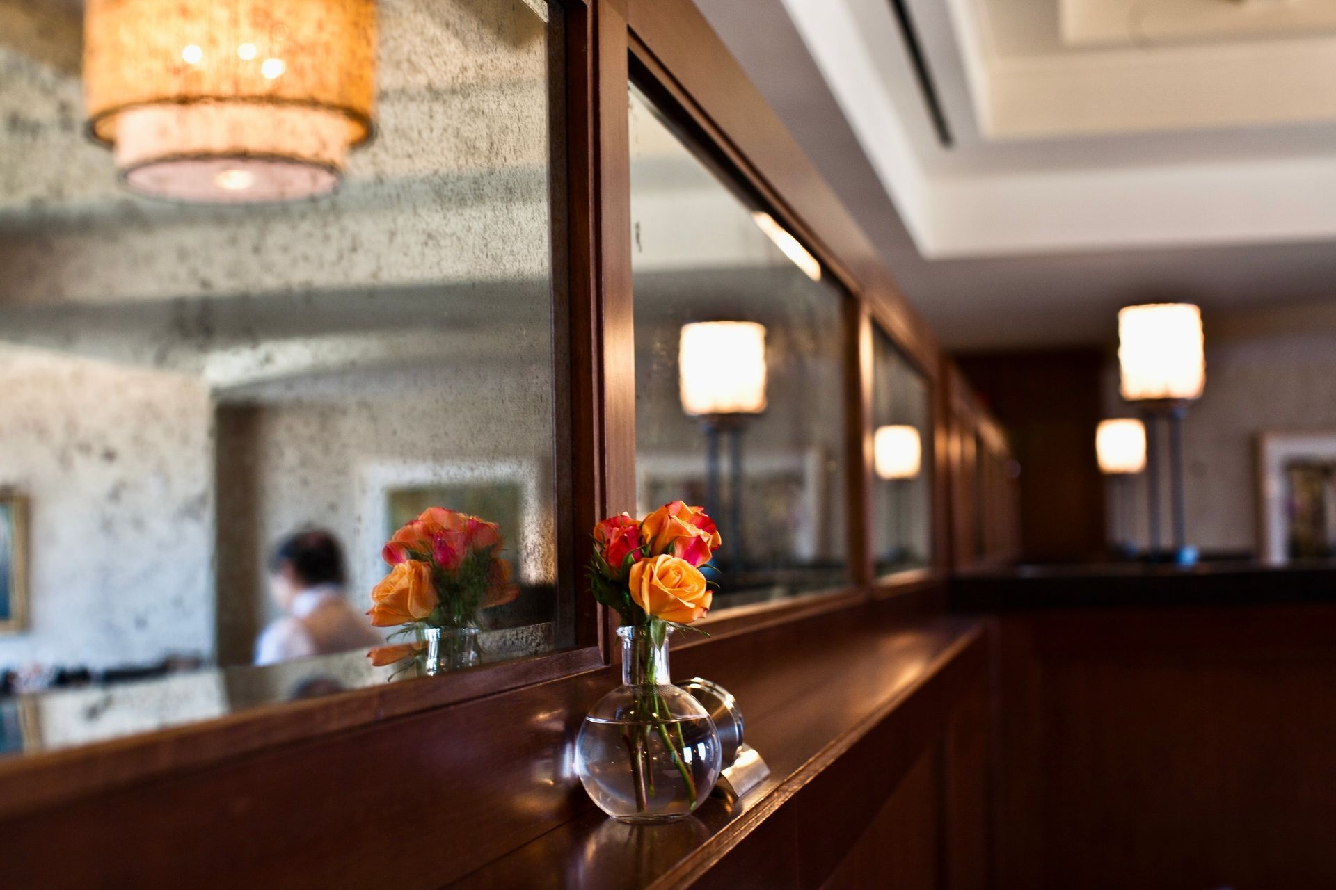 A vase of flowers is sitting on a table in front of an antique mirror.