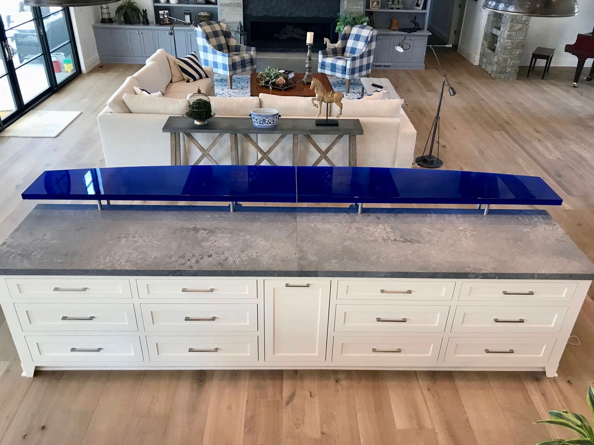 A living room with a blue glass counter top and white cabinets