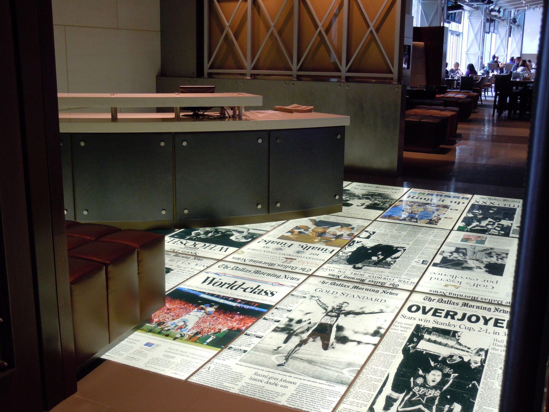 Newspaper-covered floor in a restaurant, with a bar and seating visible in the background.