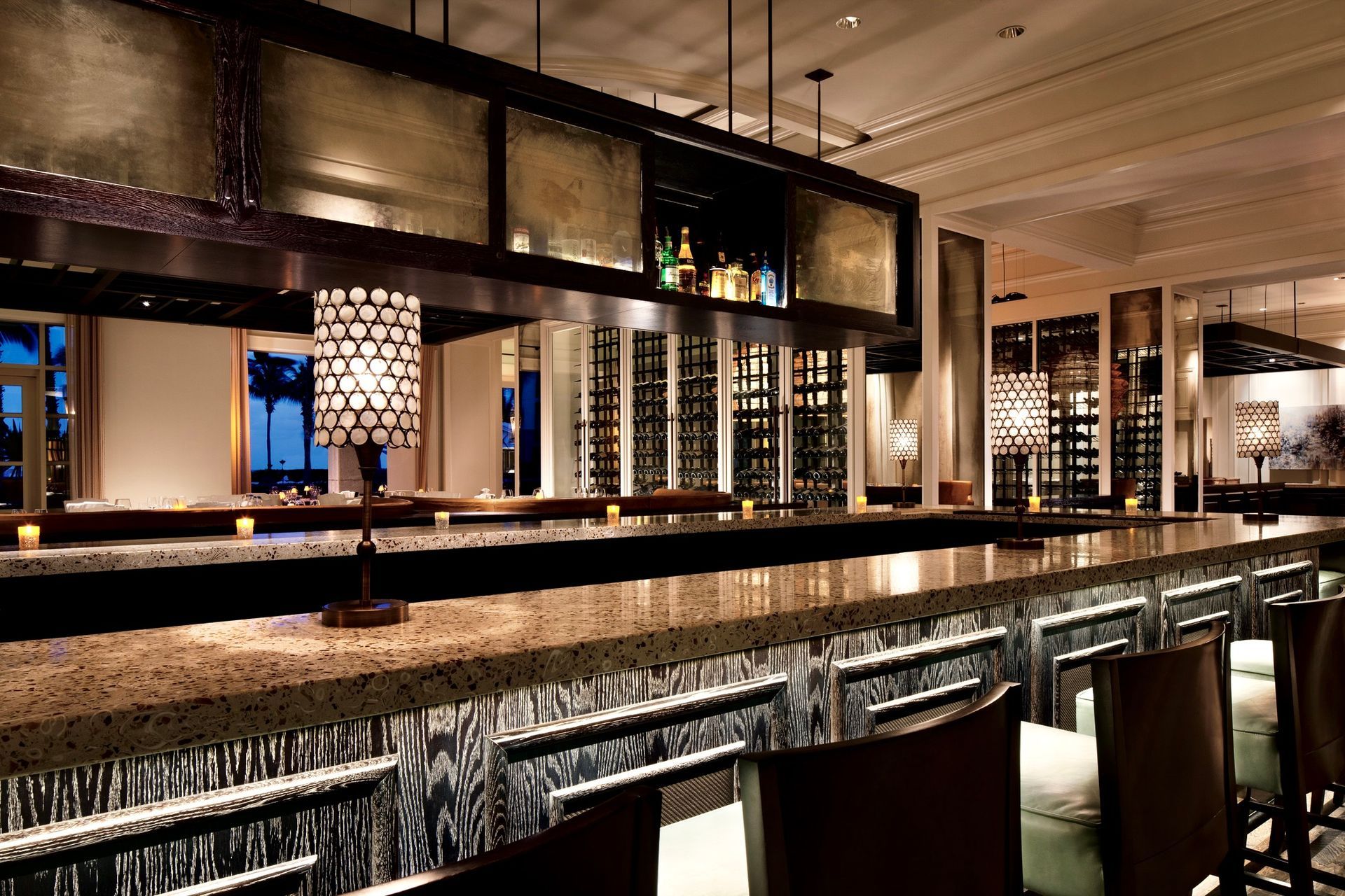A restaurant with a long bar and chairs with antique mirrors along the bar