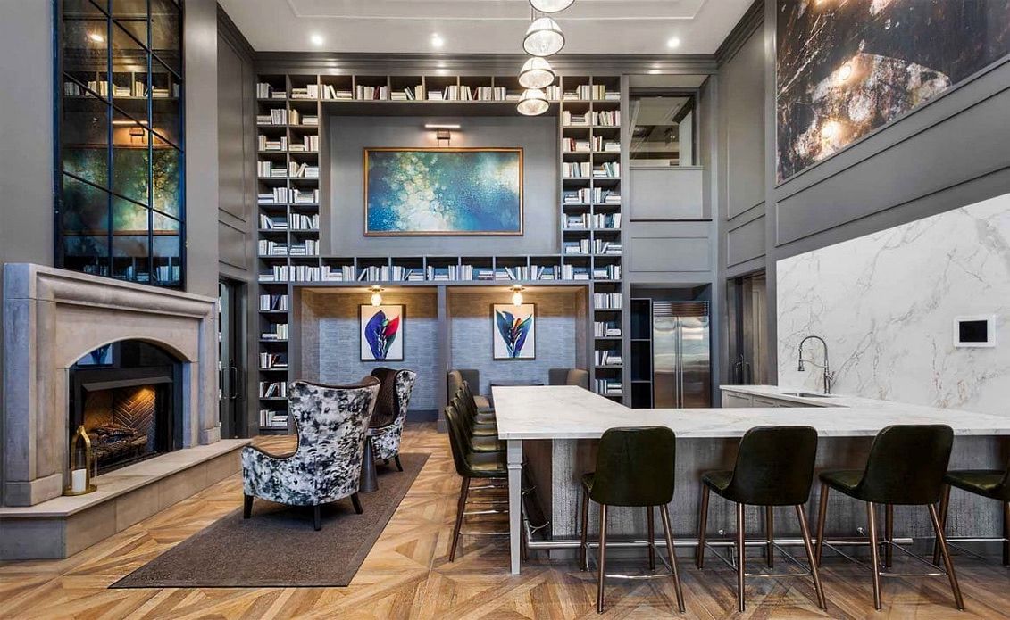 A living room with a antique mirror above fireplace and a bar