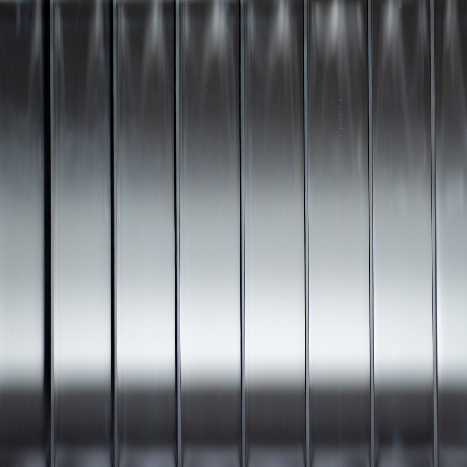 Vertical, shiny glass panels reflect light, creating a gradient effect from top to bottom.