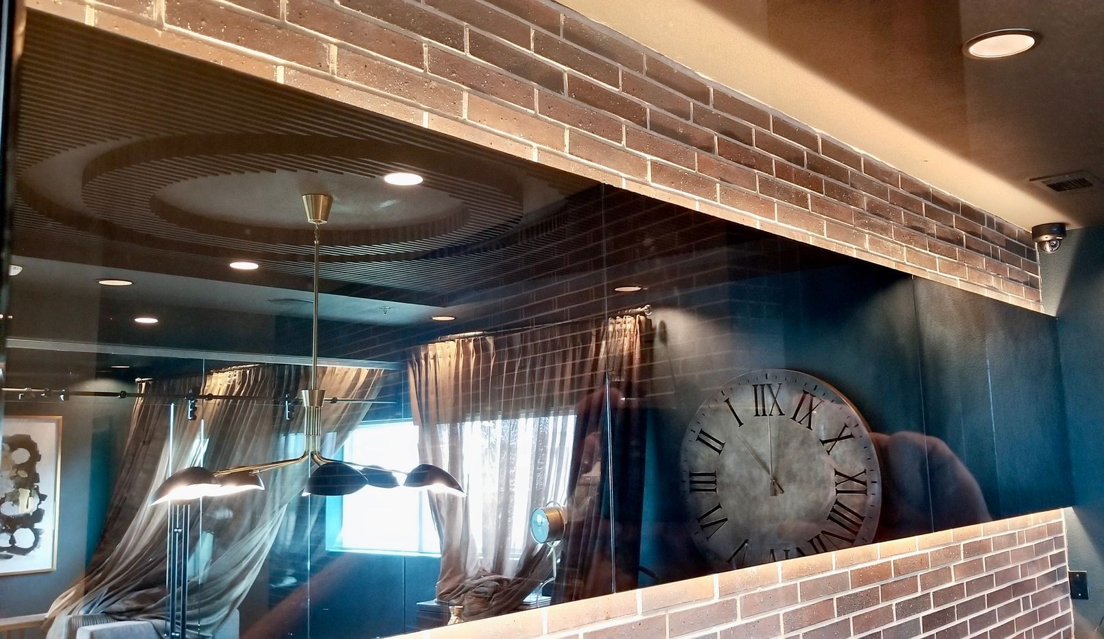 An antique mirror with a clock on it and a brick wall behind it
