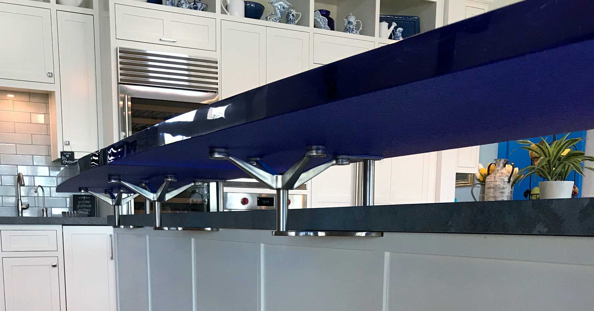 A kitchen with white cabinets and a blue glass counter top