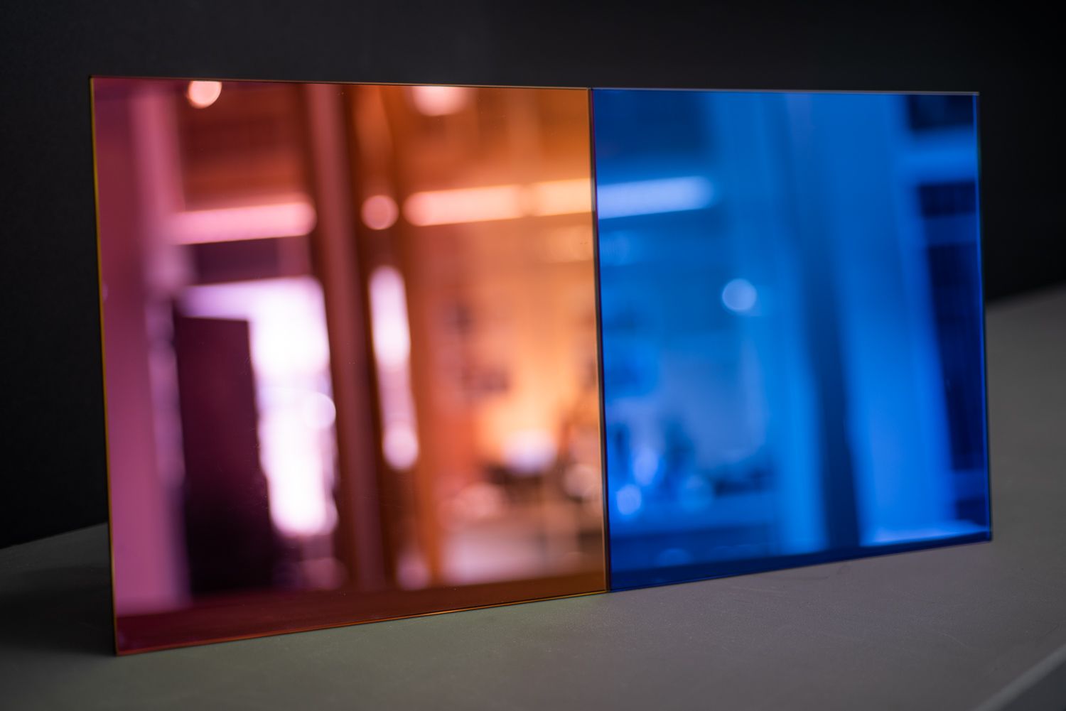 Two pieces of dichroic glass with different colors on them are sitting on a table.