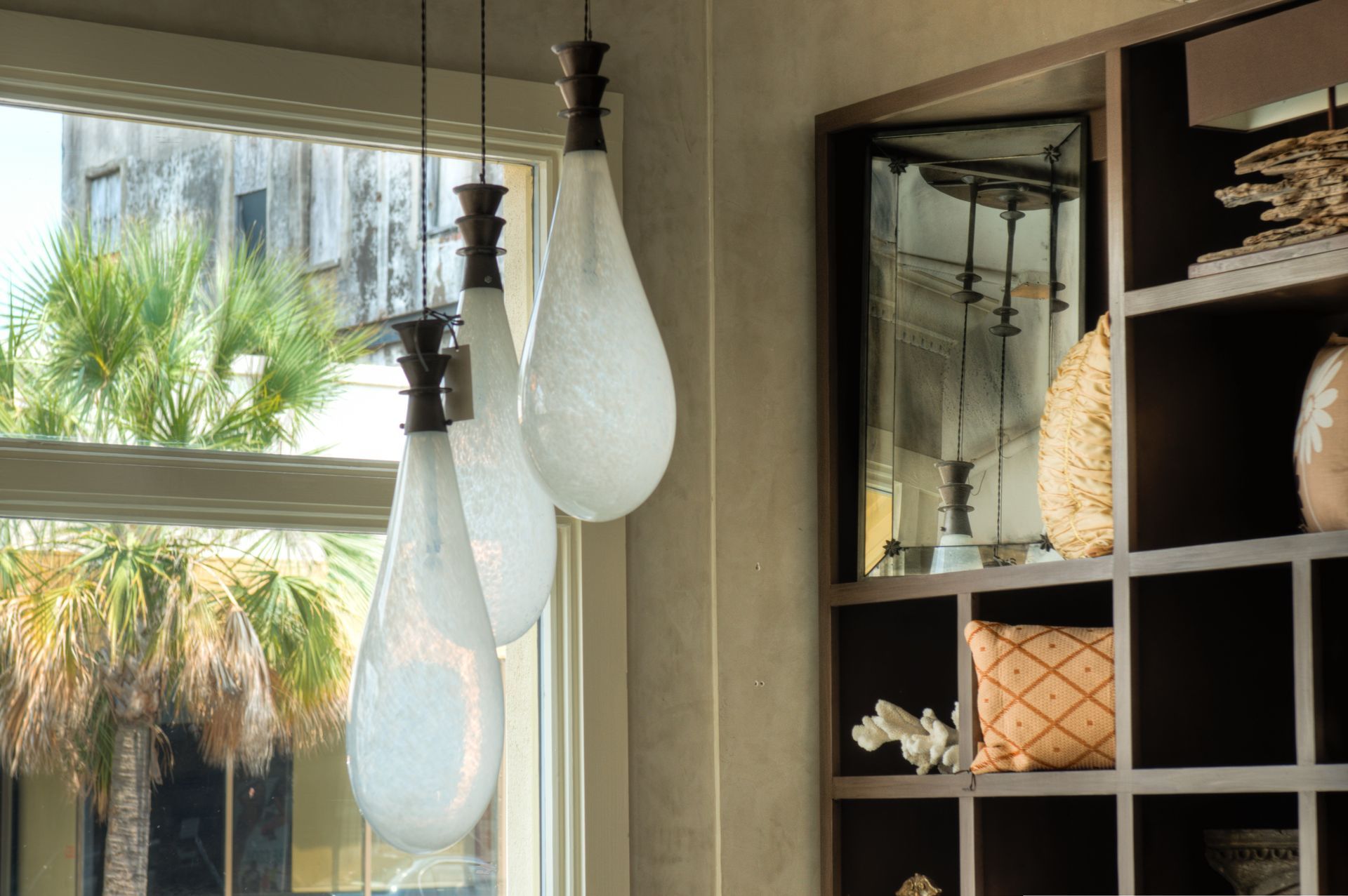 Three teardrop-shaped glass pendant lights hang in front of a window, next to a built-in shelf.