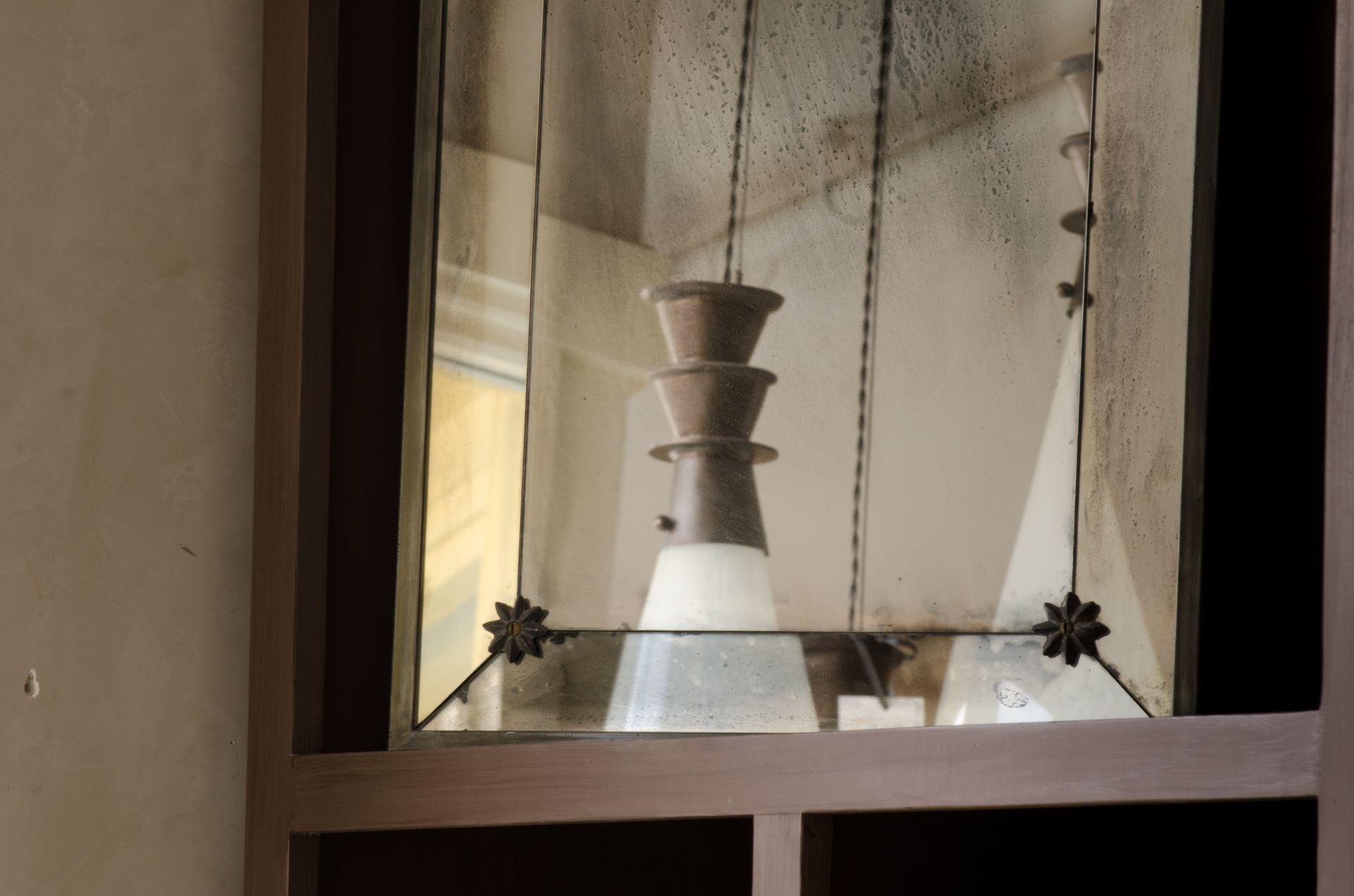 Mirror with a hanging light fixture and decorative elements; reflected room is visible.