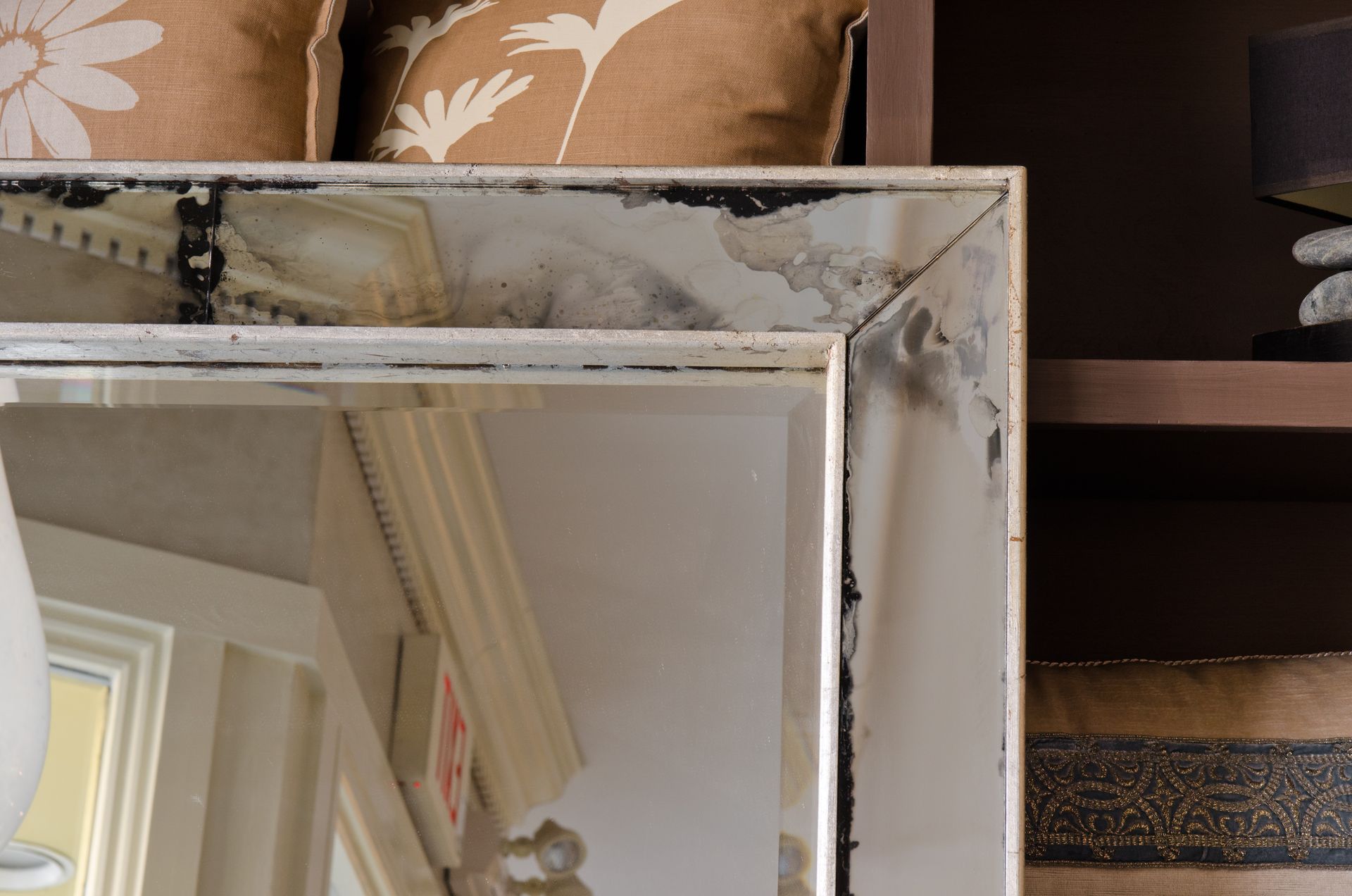 Close-up of a distressed-style mirror with an ornate frame, displaying reflections.