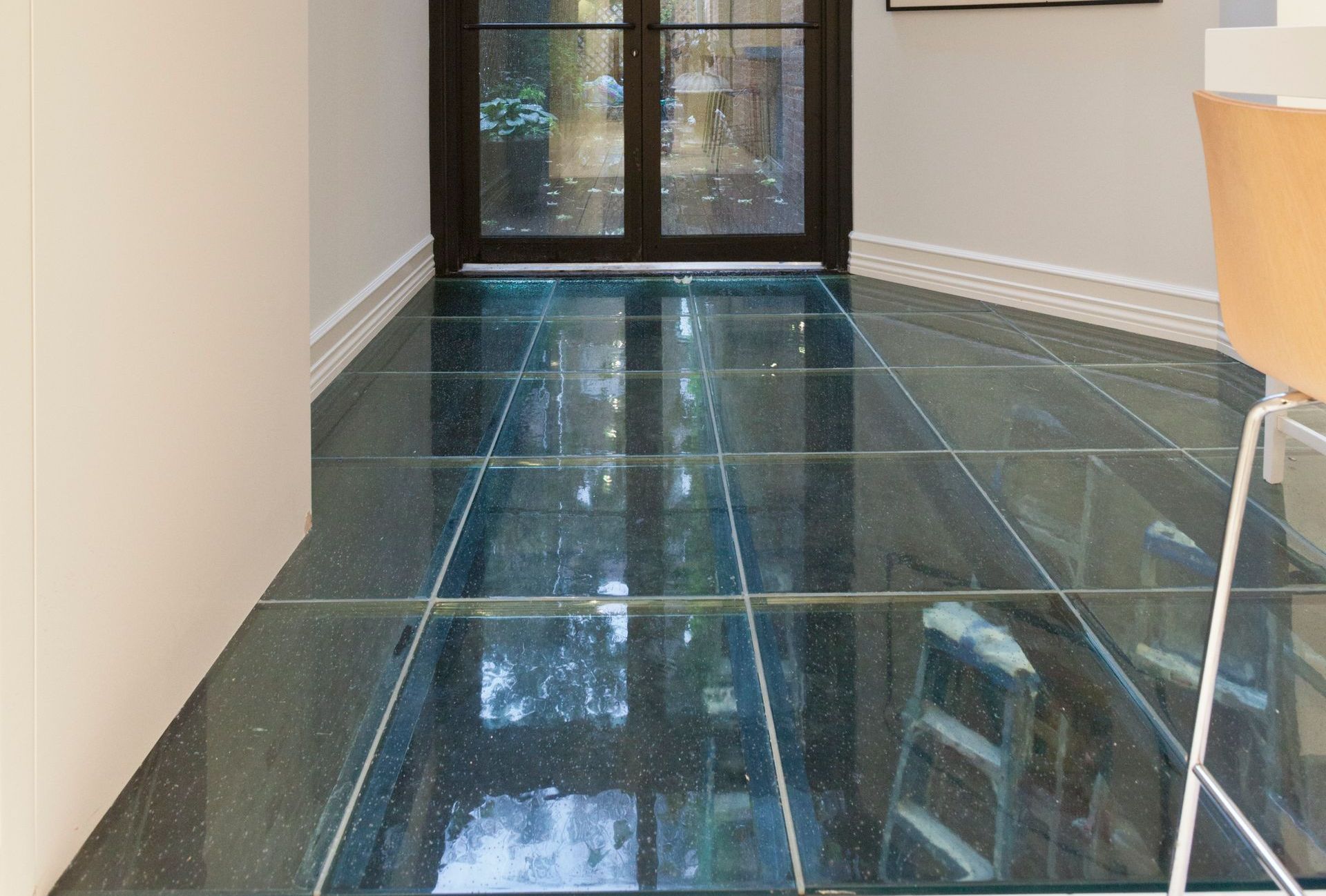 Glass floor panels reveal a space below; leading to a dark door.